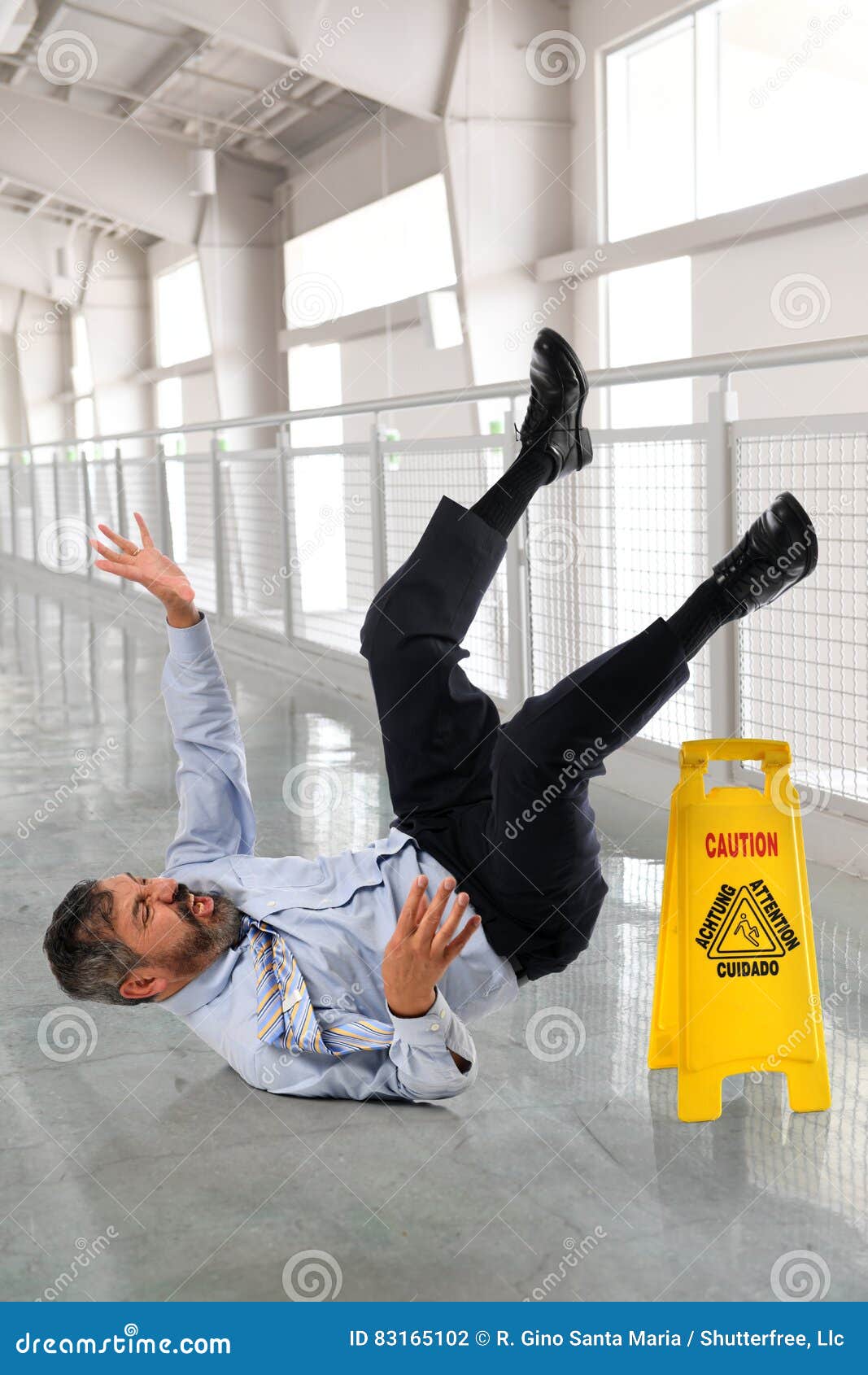 Zakenman Falling op Natte Vloer. Spaanse zakenman die op natte vloer binnen de bureaubouw vallen