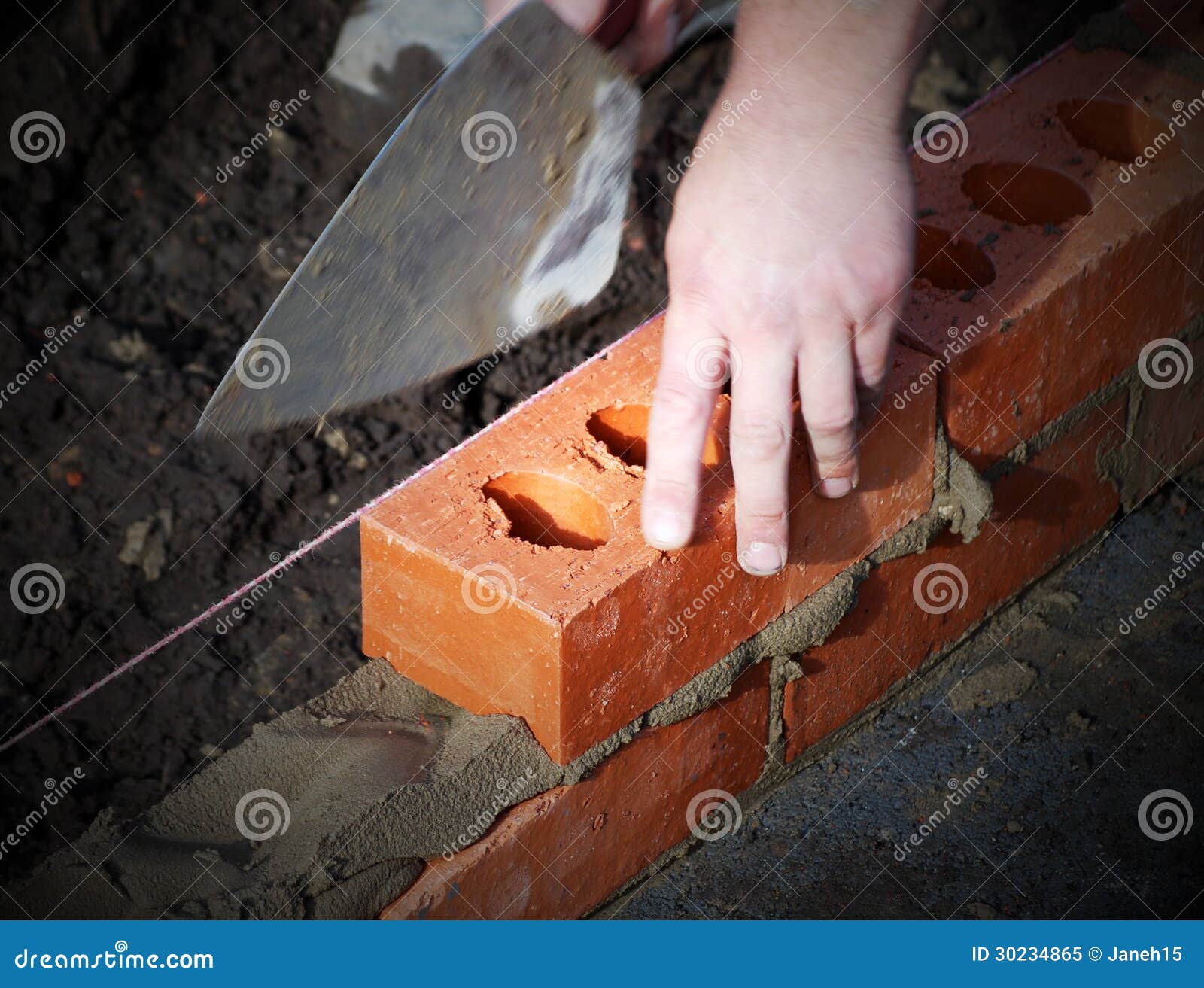 Murarz przy pracą. Zbliżenie kłaść cegły pokazuje kielnię i linię pracownik budowlany.