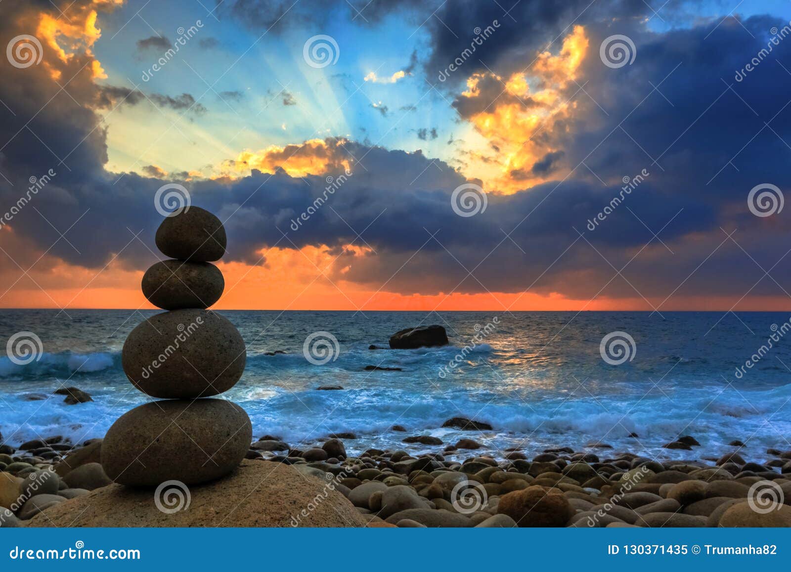 nature seascape with zen stacked rocks on beach at colorful sunrise
