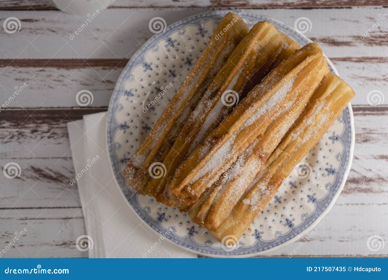 zenital view of typical hispanic churros filled with dulce de leche in a vintage plate on old boards. copy space