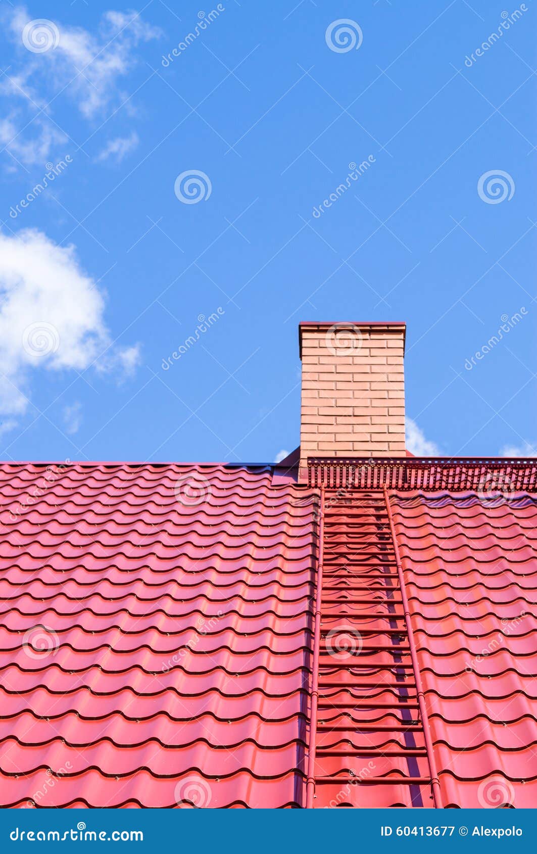 Ziegelsteinkamin auf rotem Dach mit Metallleiter gegen blauen Himmel