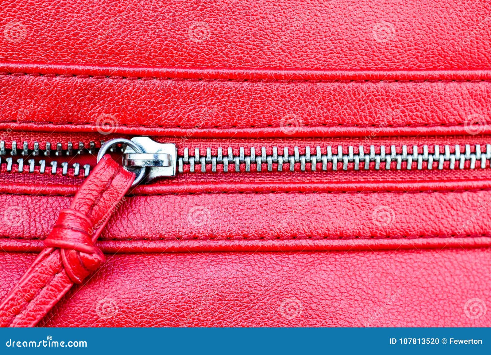 zipper partly open close up detail photo on a red leather texture background