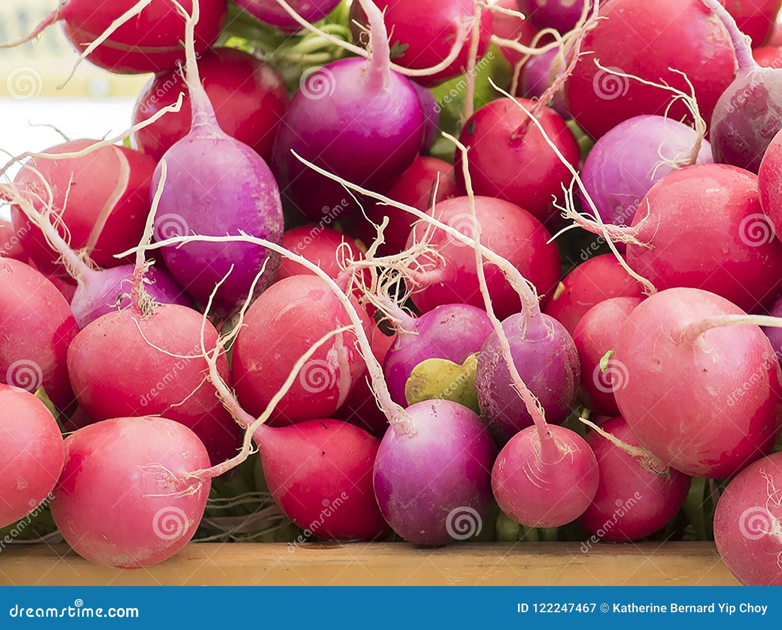 zoomed in version of multicolored radishes on a table for sale at the market