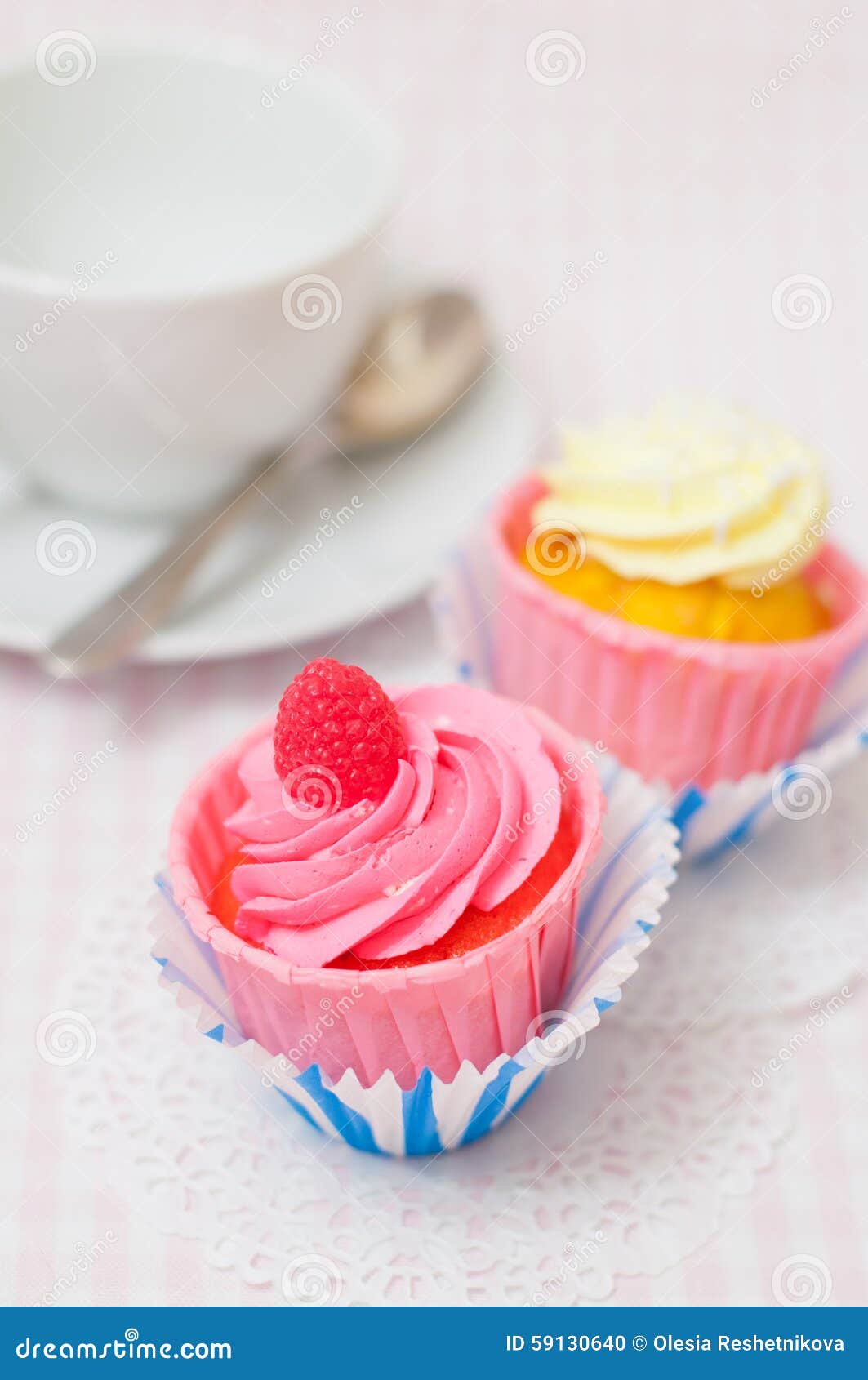 Zwei kleine Kuchen verziert mit rosa und gelber Creme auf hellrosa Hintergrund