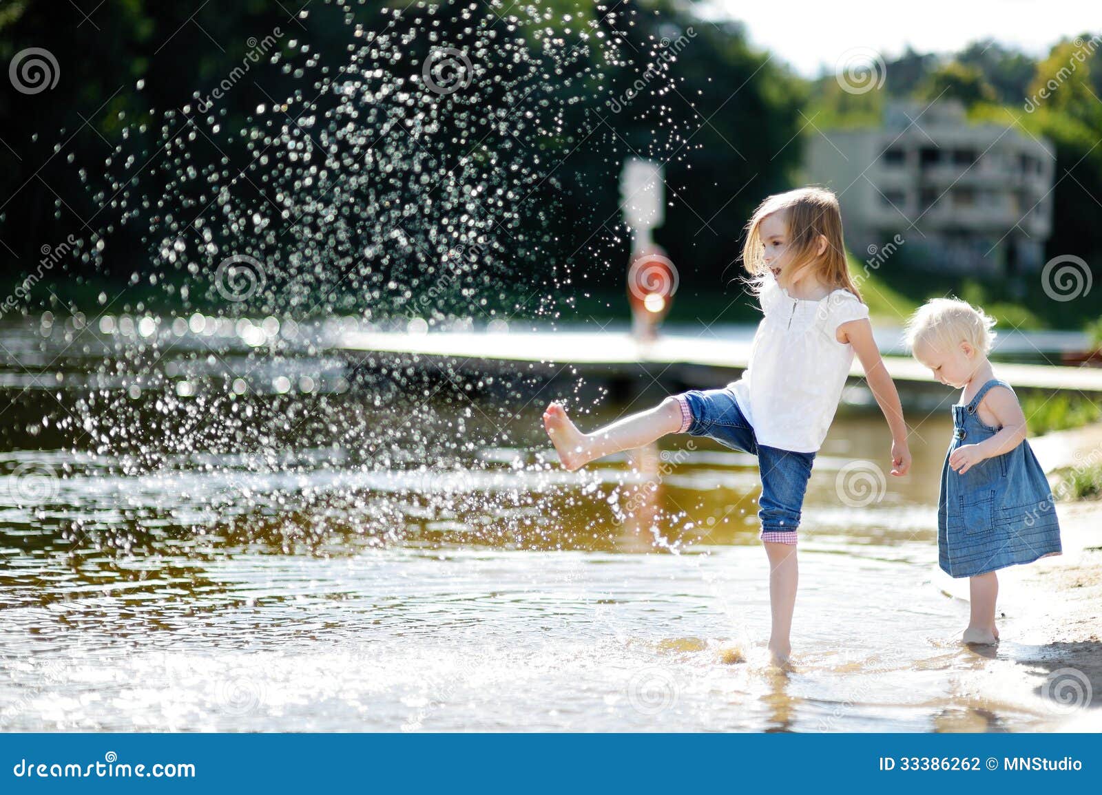 Zwei kleine Schwestern, die Spaß durch einen Fluss haben. Zwei kleine Schwestern, die Spaß durch einen Fluss am Sommer haben