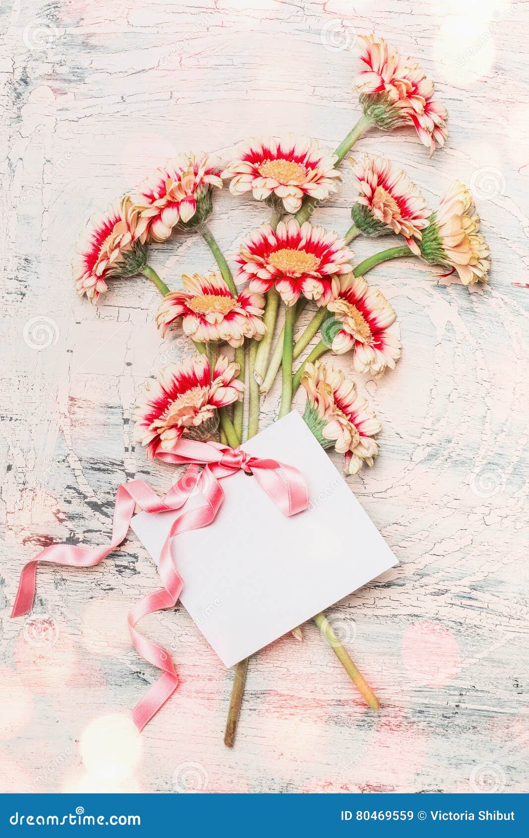 Älskvärd blommabukett med det tomma vita kortet, pilbågen och bokeh på sjaskig chic bakgrund