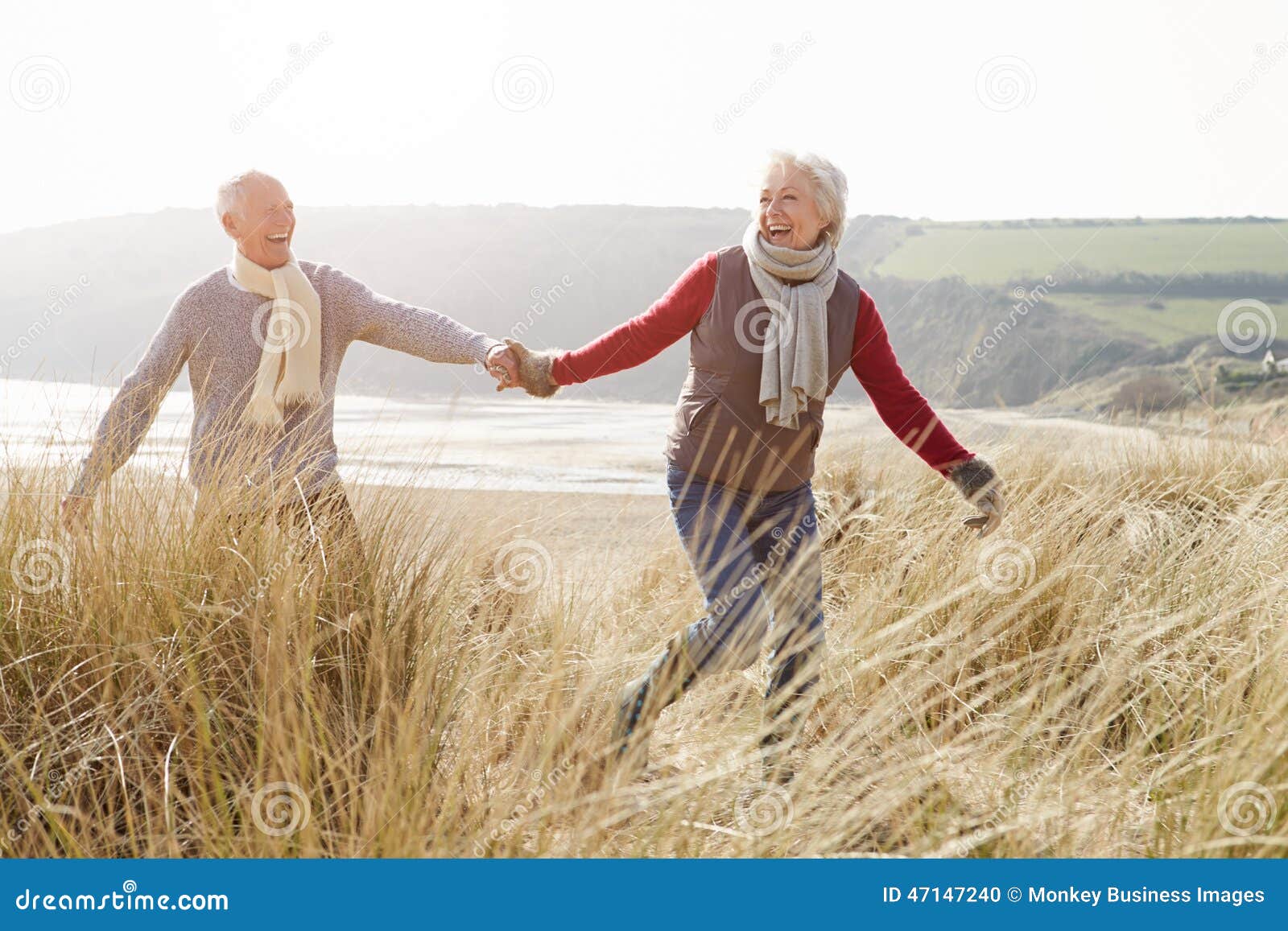 Ältere Paare, die durch Sanddünen auf Winter-Strand gehen