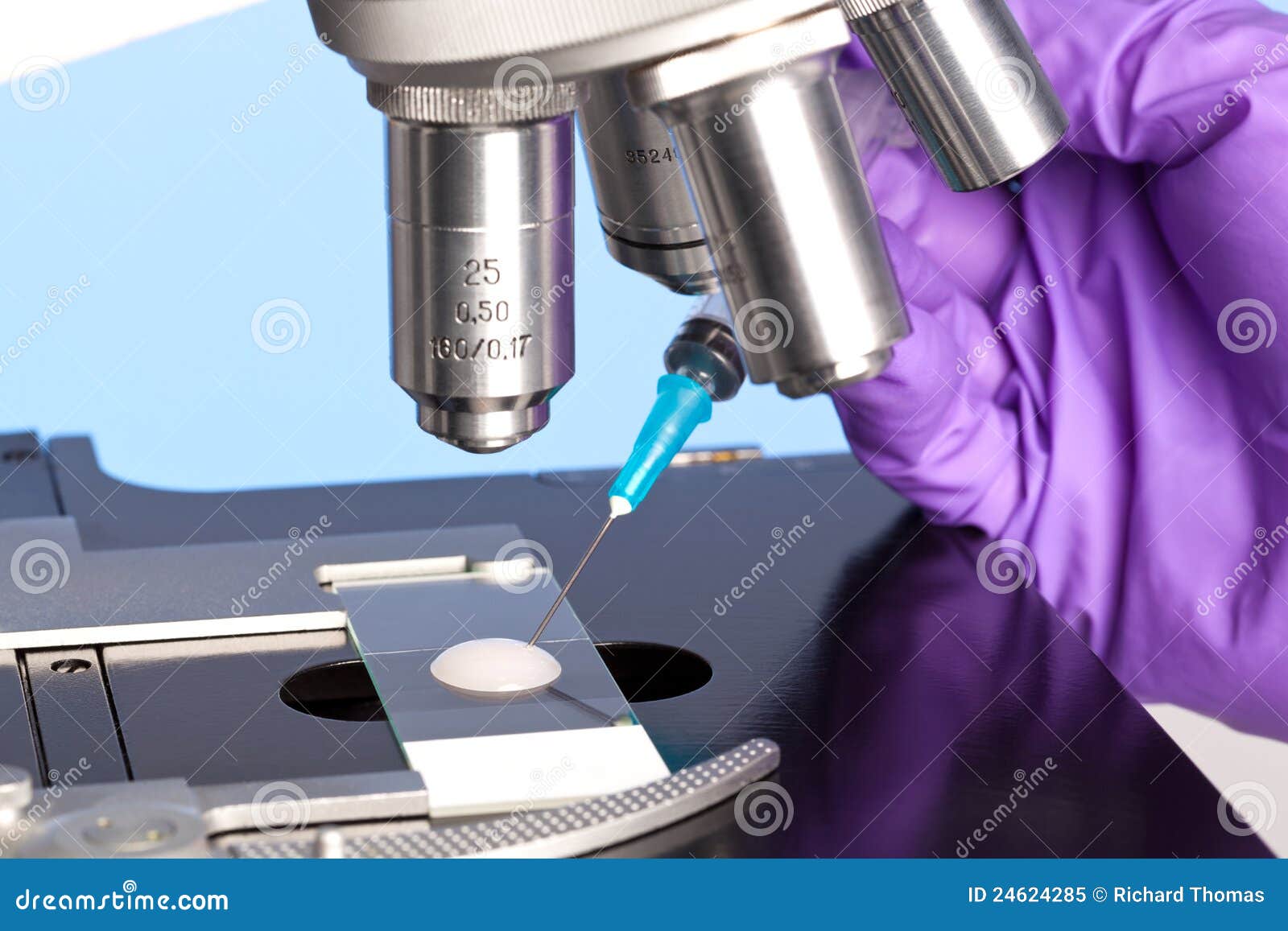 Échantillon et microscope d'embryologie. Photo d'un échantillon de sperme sur une glissière de microscope avec une seringue étant utilisée pour extraire un spécimen d'embryologie pour l'analyse.