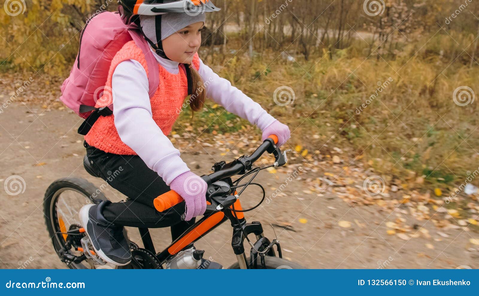 Één Kaukasische de fietsweg van kinderenritten in de herfstpark Het meisje die zwarte oranje cyclus in bosjong geitje berijden gaat doet fietssporten De rit van de fietsermotie met rugzak en helm Bergfiets hardtail