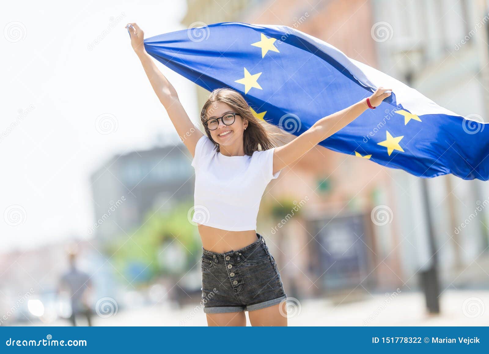 Śliczna szczęśliwa młoda dziewczyna z flagą unia europejska w ulicach gdzieś w Europe, ludzie, brexit błękitny, piękny, biały, mały, piękno, kobieta, osoba, uśmiech, portret, symbol, ładny, stawia czoło, podróżuje, trzymać, rozochocony, miasto, wyrażenie, brusel, pomyślny, inteligencja, patriota, plenerowy, turystyka, turysta, miasteczko, miejsce przeznaczenia, stojak, skok, bieg caucasian, szalony, kobieta, uczeń, wolność, dziecko, dzieciństwo, dzieciak