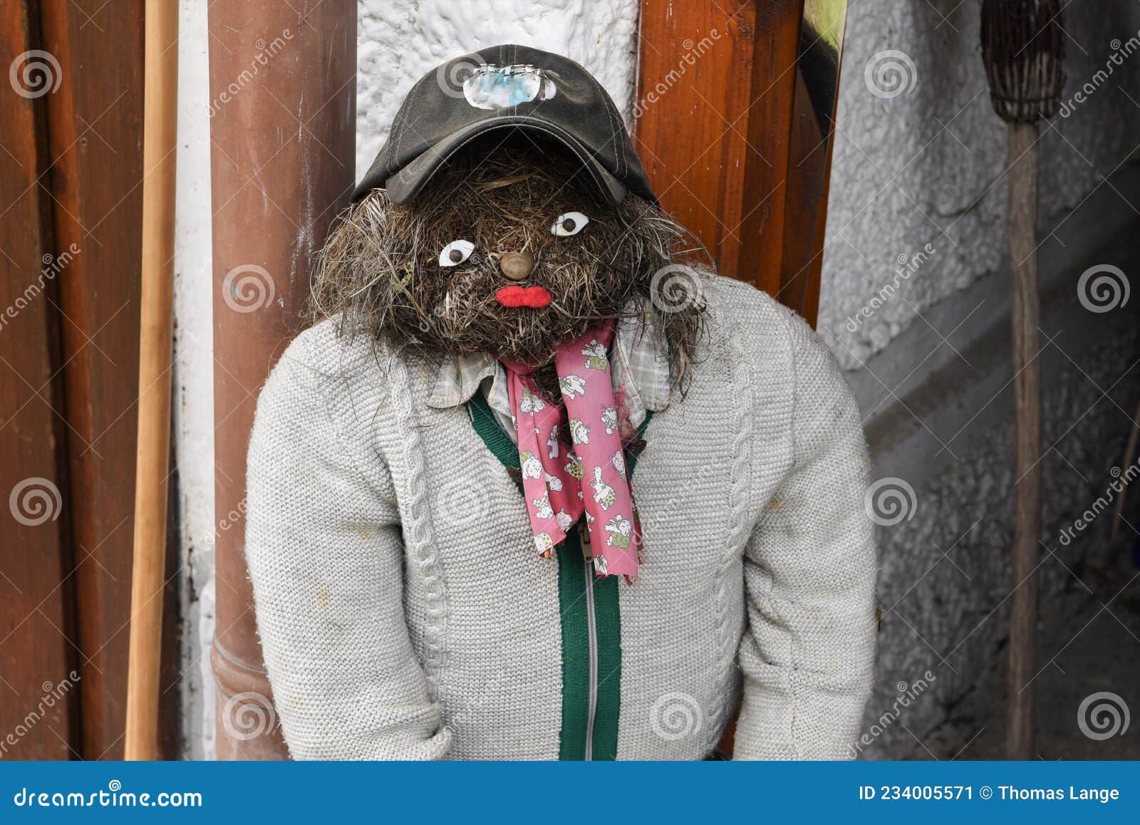 ένας άνδρας φτιαγμένος από άχυρο με κάπα και πλεκτό πανωφόρι και μια αρχικά και διακοσμητική αδέσποτη κούκλα