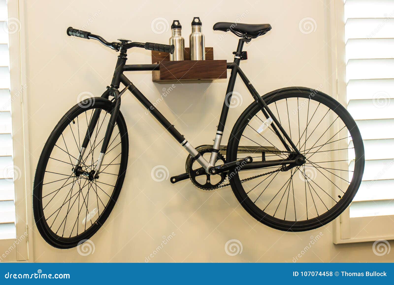 Ένωση ποδηλάτων από τον τοίχο. Διακοσμητικοί ποδήλατο, κάτοχος και μπουκάλια νερό που δίνουν στον τοίχο κρεβατοκάμαρων στο σύγχρονο σπίτι