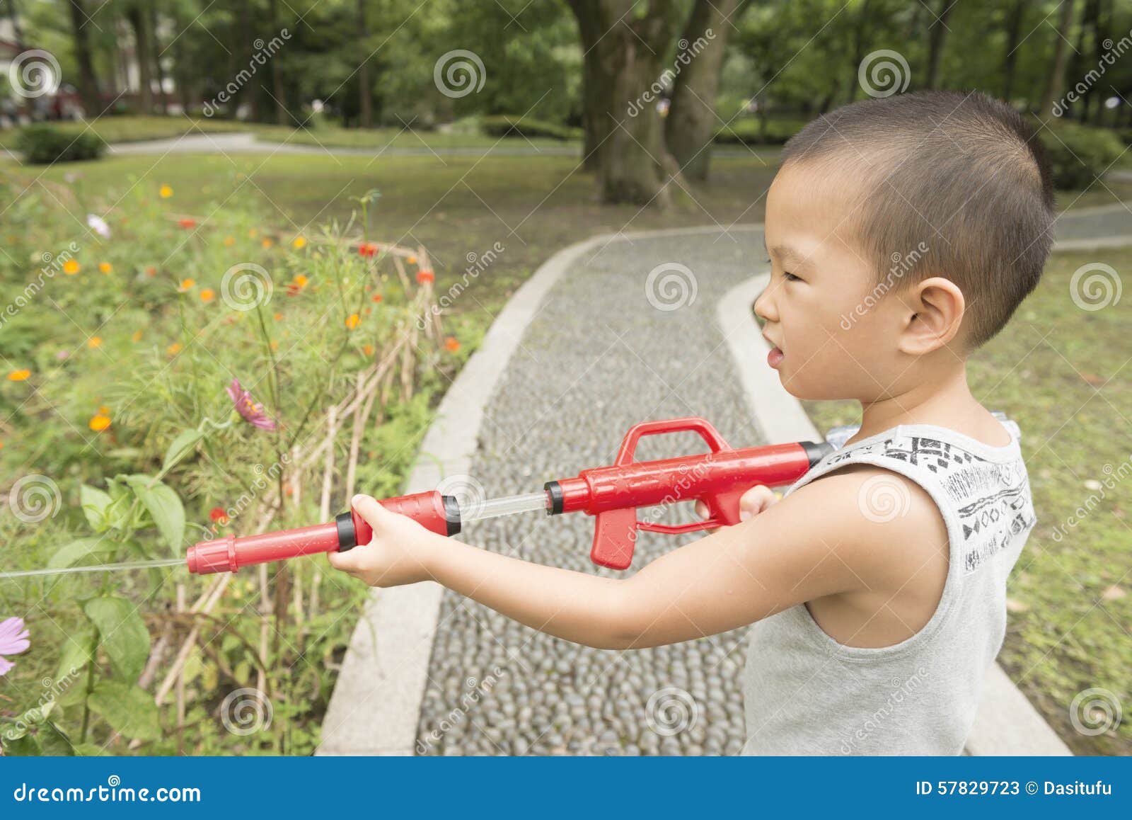 Αγόρι όπως τον πράκτορα της ασφάλειας. Κινεζικό ευτυχές πυροβόλο όπλο νερού παιχνιδιού αγοριών στο πάρκο