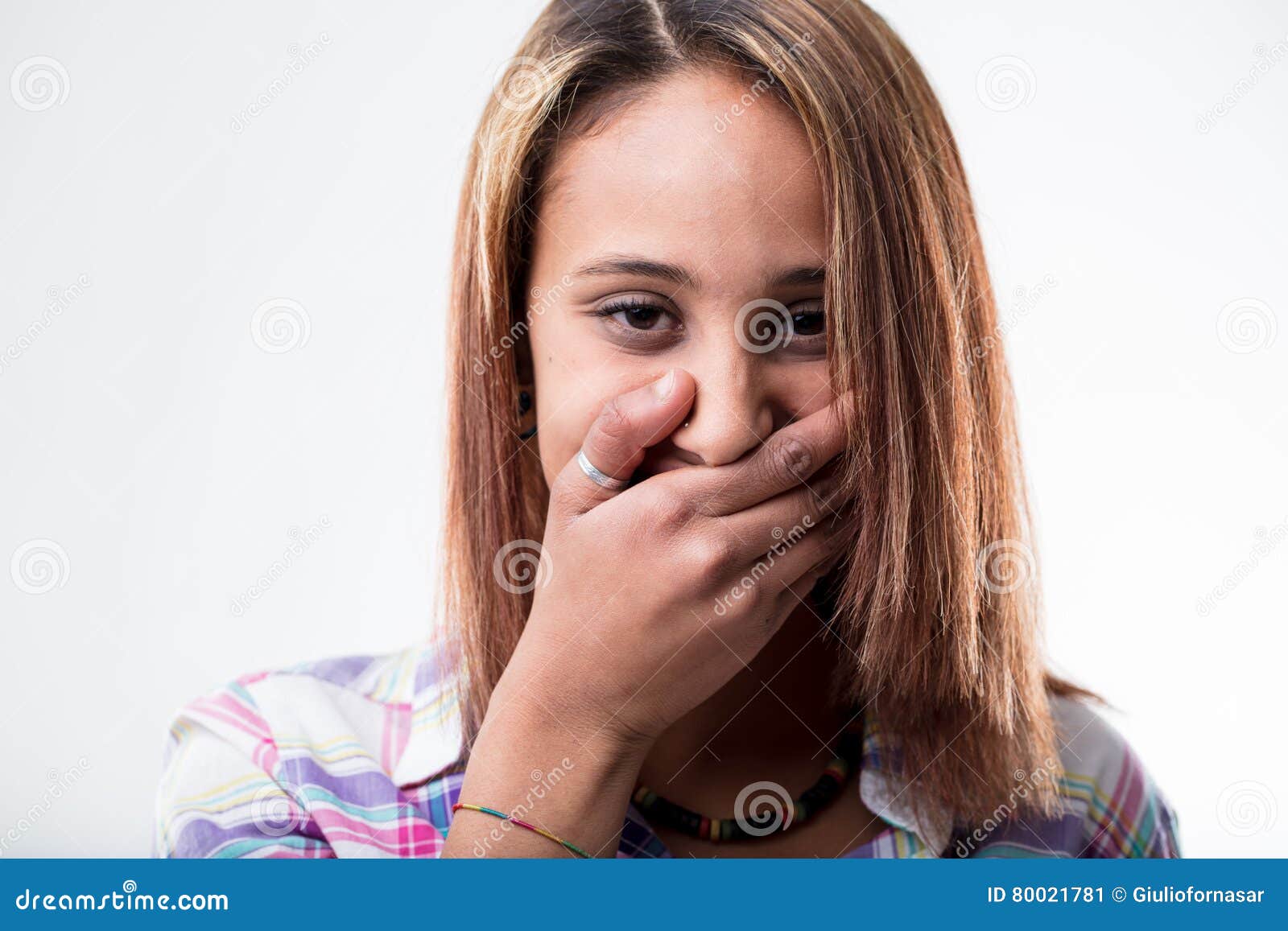 Αμήχανη νέα γυναίκα που καλύπτει το στόμα της με το χέρι της για να πνίξει τα giggles της ή να κρύψει τον κλονισμό της