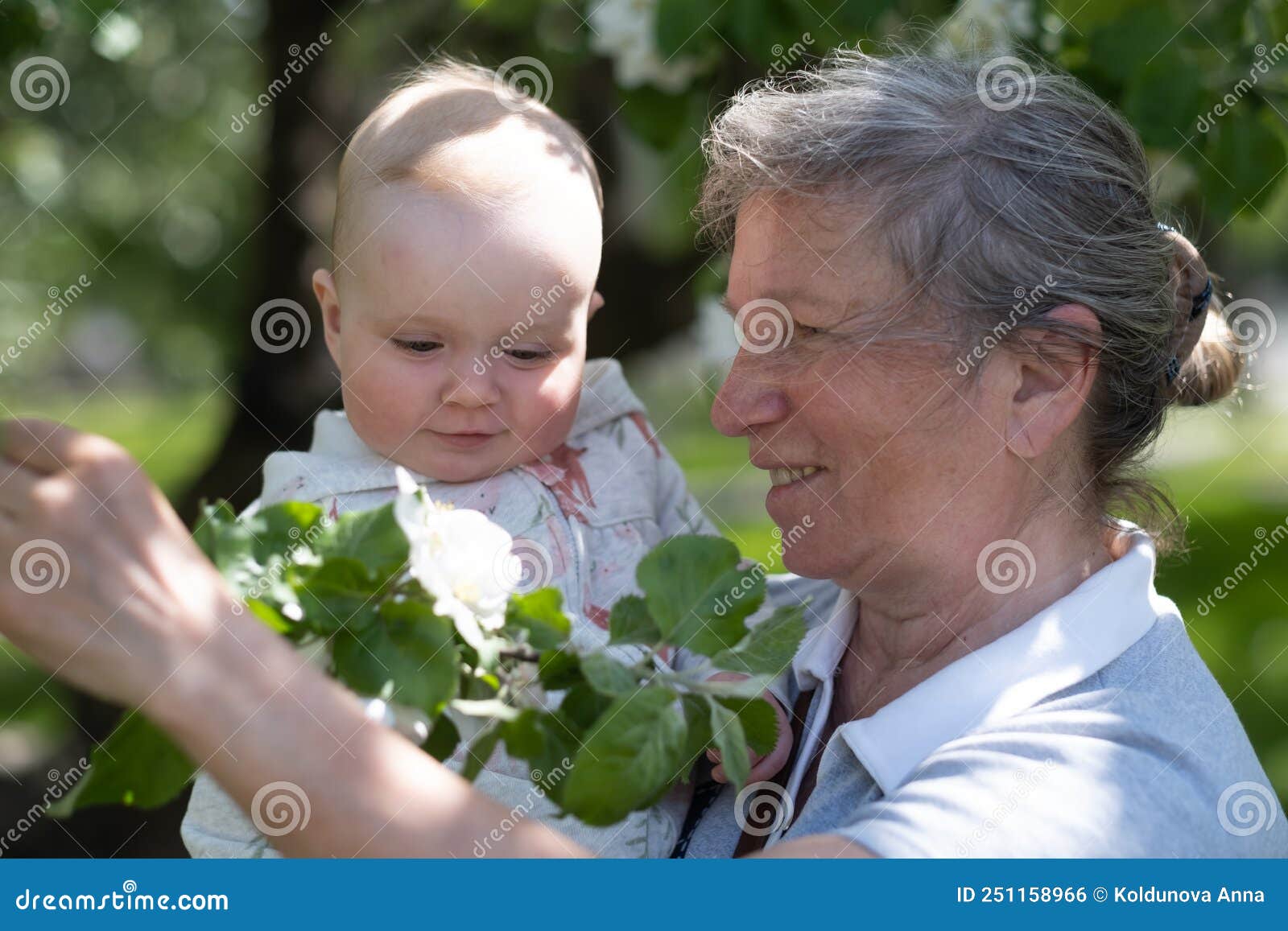 γιαγιά που περπατάει με την εγγονή της έξω στο πάρκο στις αρχές του καλοκαιριού