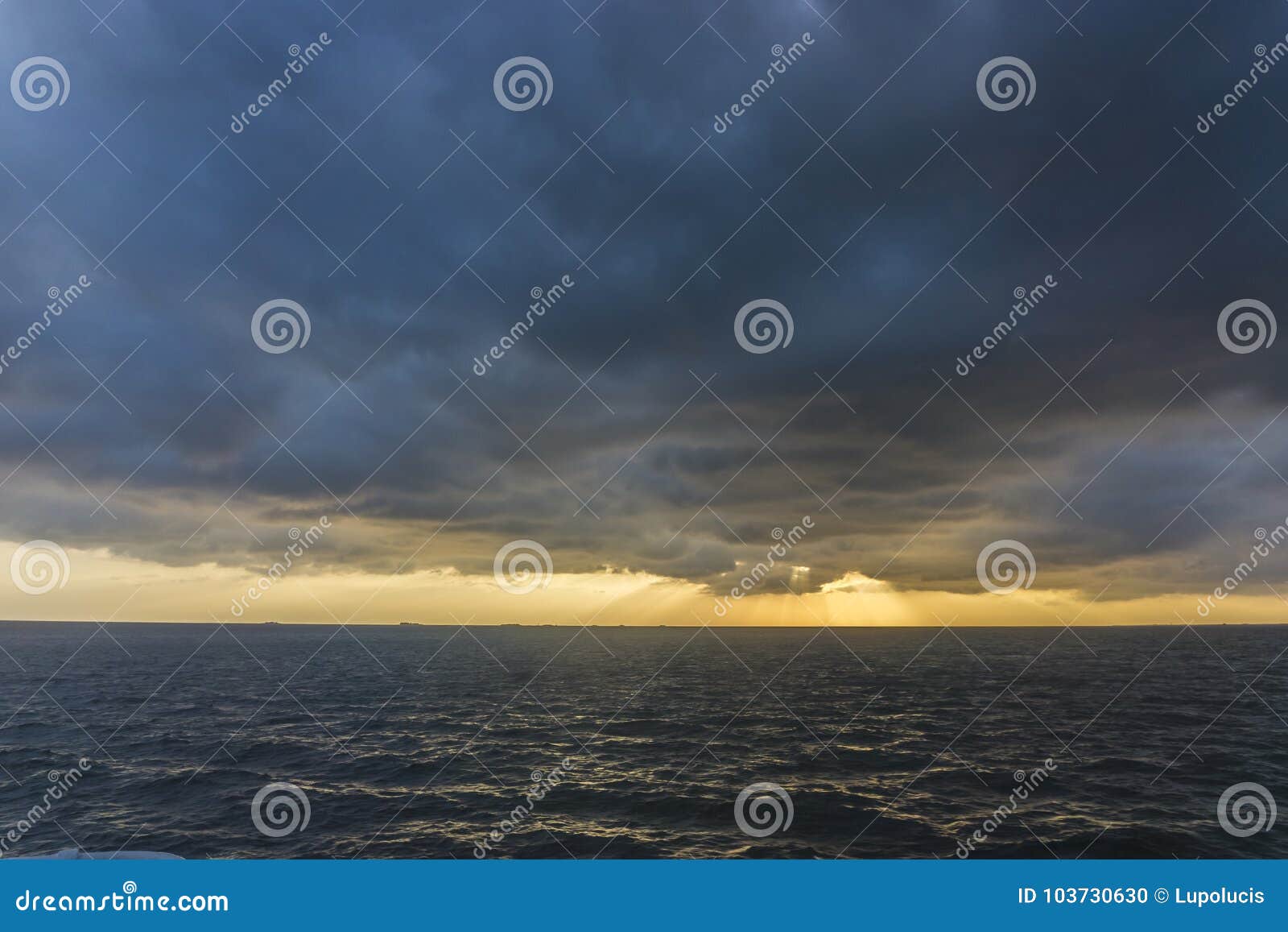Δραματικό ηλιοβασίλεμα στη Βόρεια Θάλασσα με τις βαθιές νεφελώδεις ηλιαχτίδες ουρανού μέσω των σύννεφων και αντανακλάσεις στη θάλασσα
