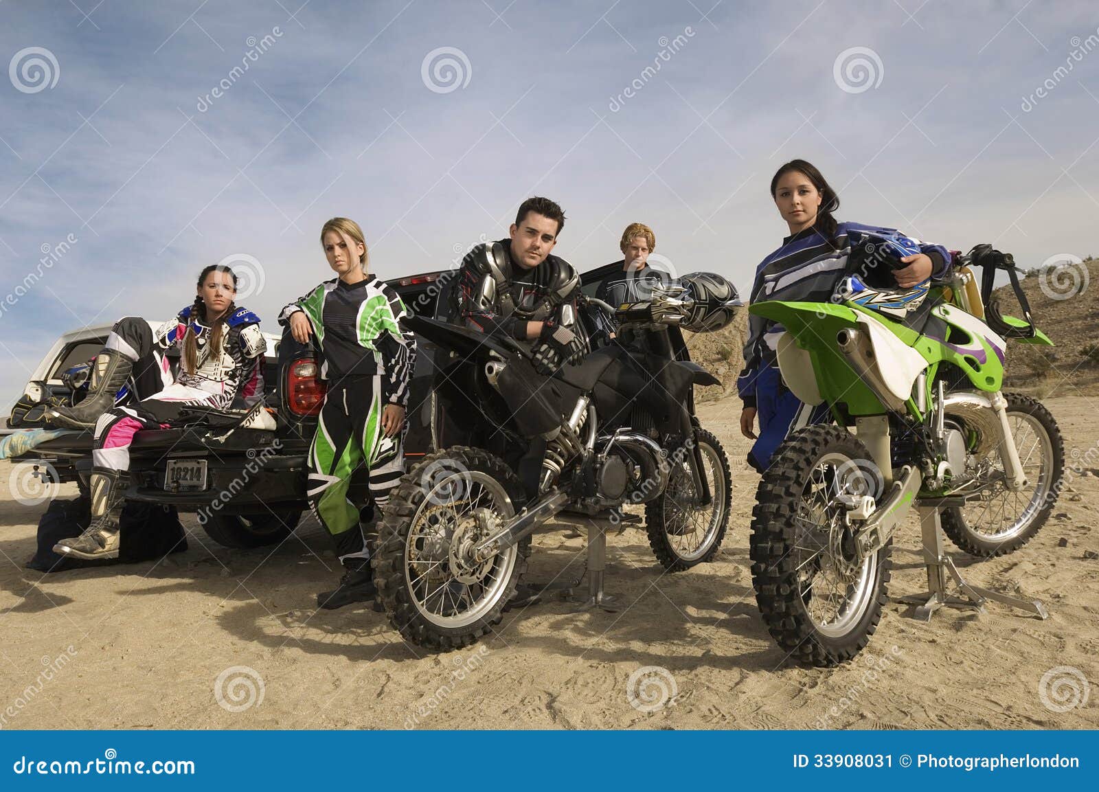 Δρομείς μοτοκρός με τις μοτοσικλέτες και ανοιχτό φορτηγό στην έρημο. Πορτρέτο των βέβαιων δρομέων μοτοκρός με τις μοτοσικλέτες και του ανοιχτού φορτηγού στην έρημο