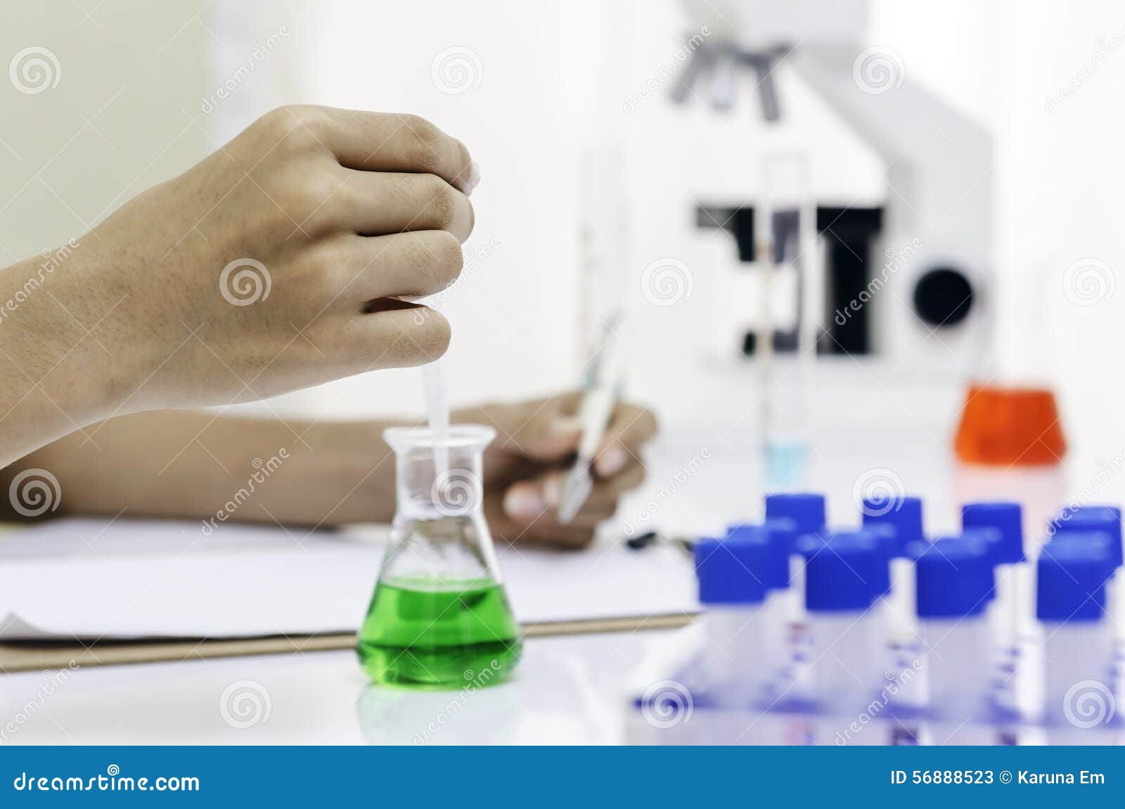 Εργαστήριο ερευνητών. Χέρι Researcherâ€™s που ρίχνει ένα πράσινο υγρό σε μια κούπα