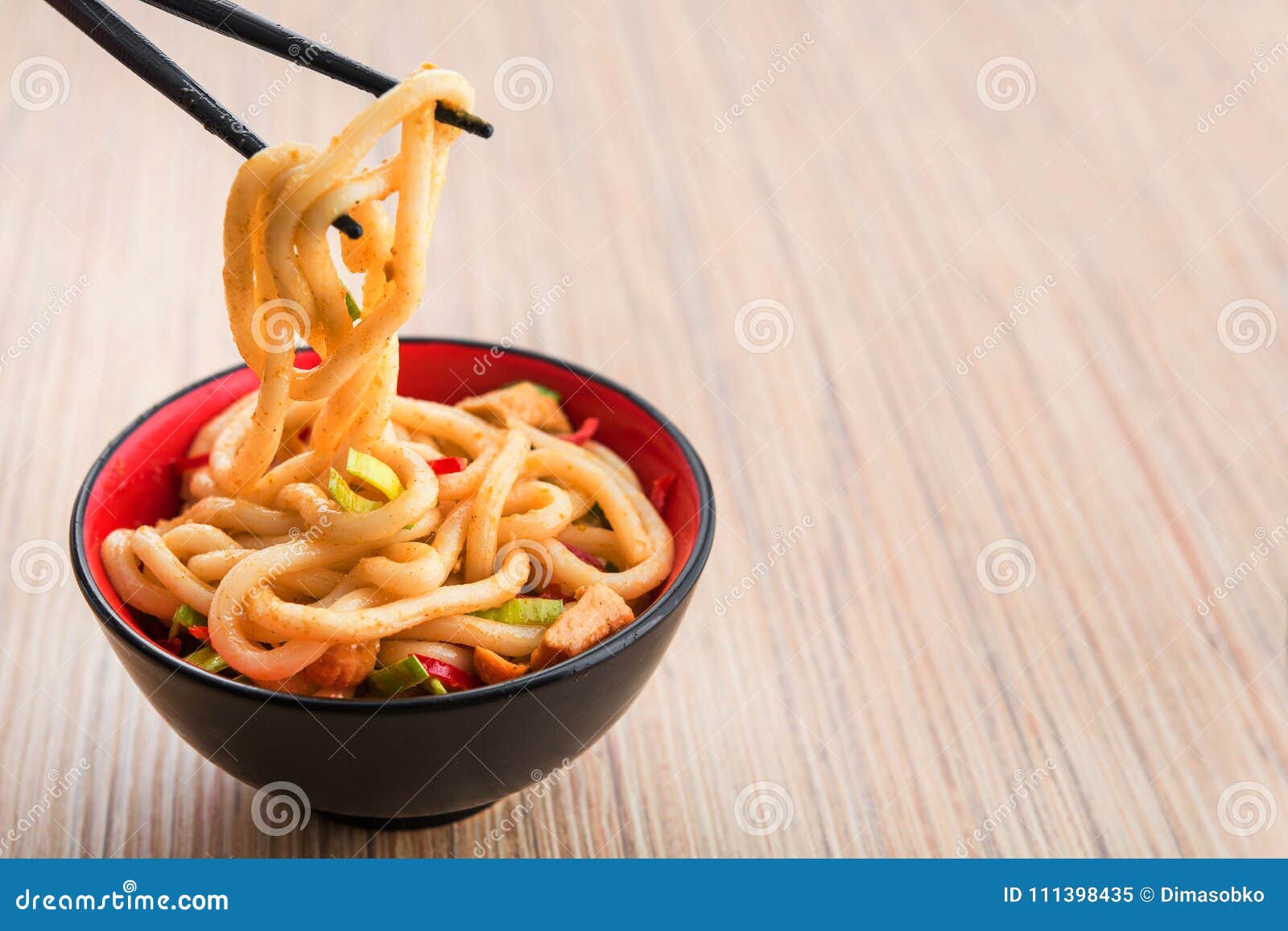 Ιαπωνικά νουντλς udon με chopstick και το κόκκινο πιπέρι σε ένα υπόβαθρο πικάντικο ιαπωνικό γεύμα