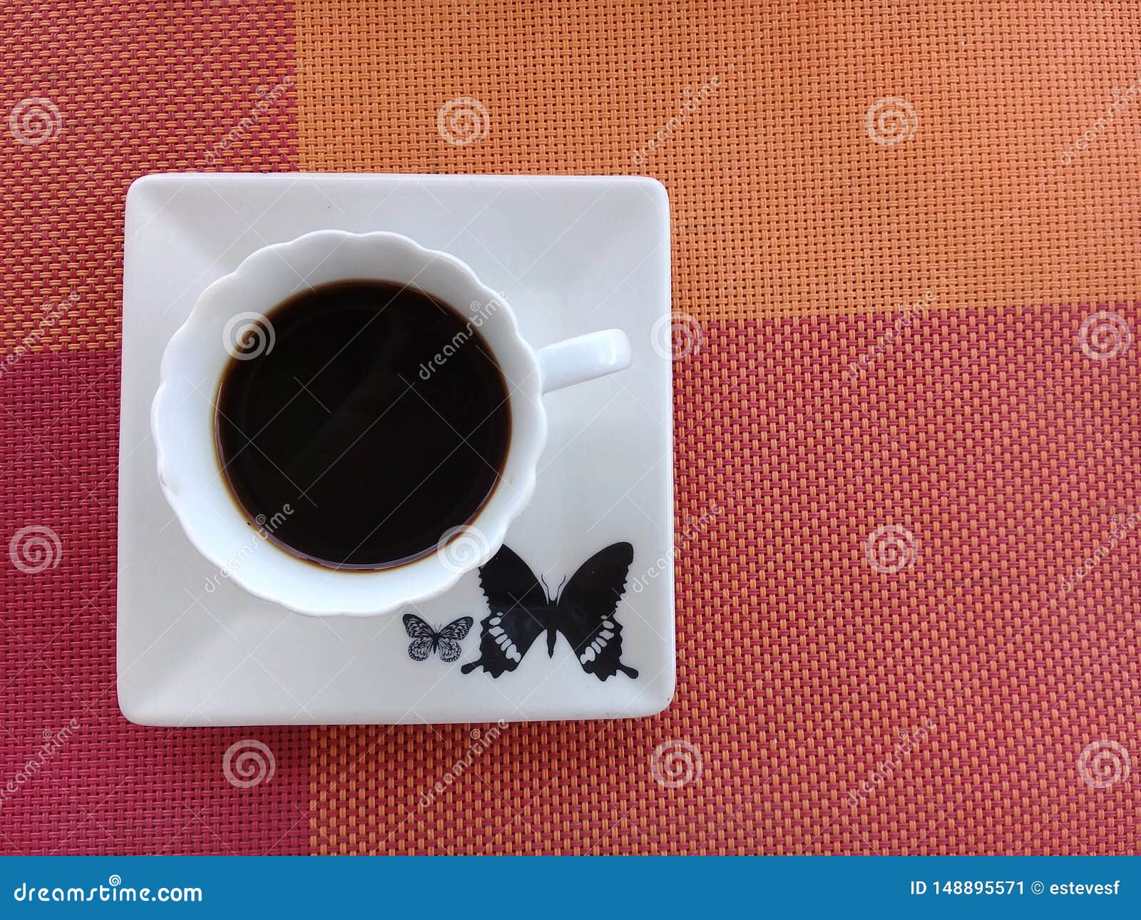 Καφές πάνω από ένα πιατάκι με το σχέδιο πεταλούδων με το χρωματισμένο υπόβαθρο