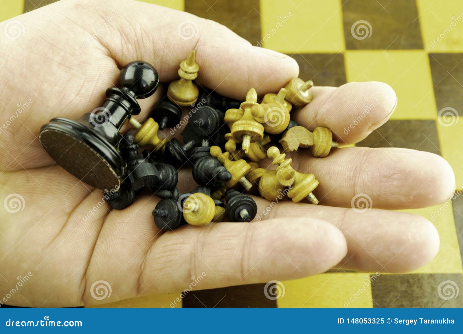 Μικρά ξύλινα κομμάτια σκακιού και ένα μεγάλο μαύρο ενέχυρο στο χέρι ενός φορέα σκακιού