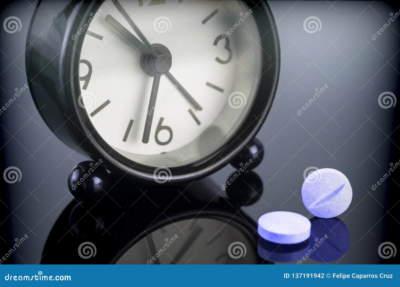 Μπλε χάπια δίπλα σε ένα ρολόι, εννοιολογική εικόνα