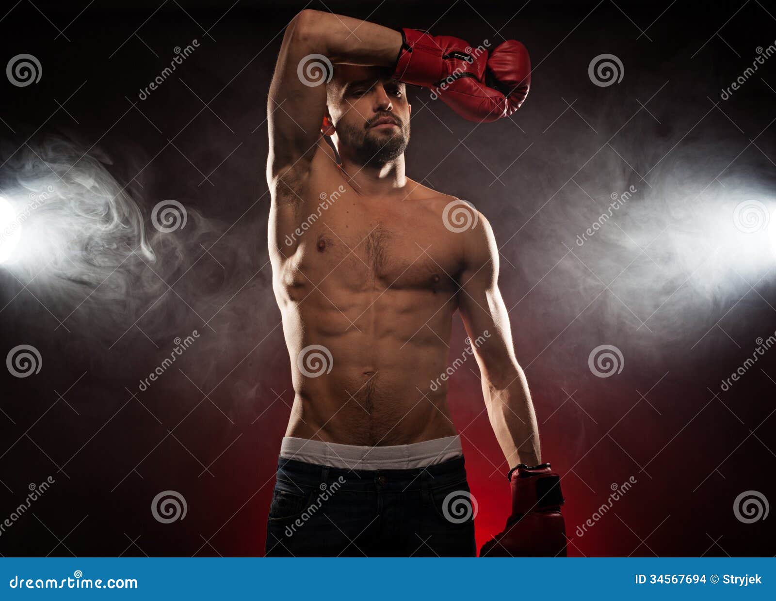 Μπόξερ που σκουπίζει το brow του κατά τη διάρκεια μιας πάλης όπως στέκεται στη γωνία του να καθαρίσει τον ιδρώτα από τα μάτια του σε μια καπνώή ατμόσφαιρα