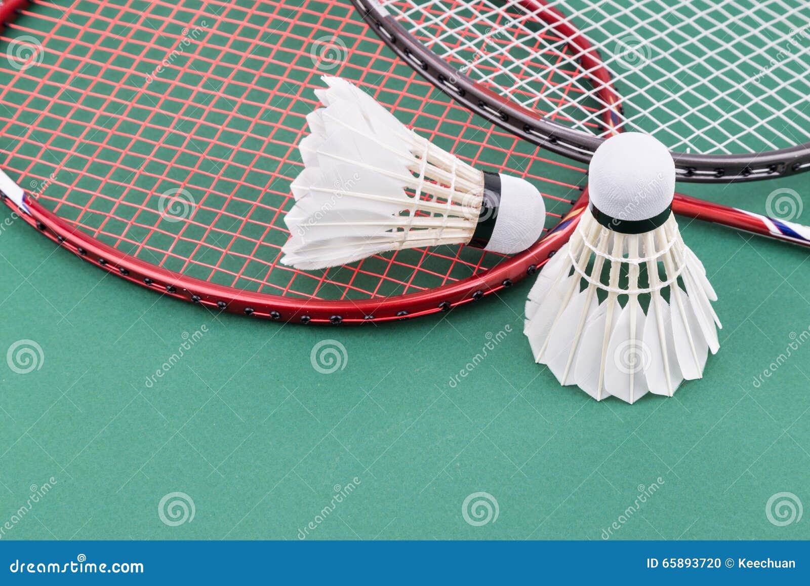 Νέο μπάντμιντον δύο Shuttlecock με τις ρακέτες στο πράσινο δικαστήριο