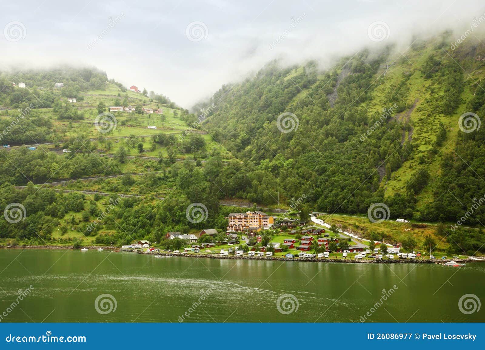 GEIRANGER - 28 ΙΟΥΝΊΟΥ: Ξενοδοχείο και βουνό φιορδ Grande στην ομίχλη στις 28 Ιουνίου 2011 σε Gieranger, Νορβηγία. Το ξενοδοχείο που βρέθηκε κοντά στο φιορδ Geiranger, συνέχισε τον κατάλογο παγκόσμιων κληρονομιών της ΟΥΝΕΣΚΟ.