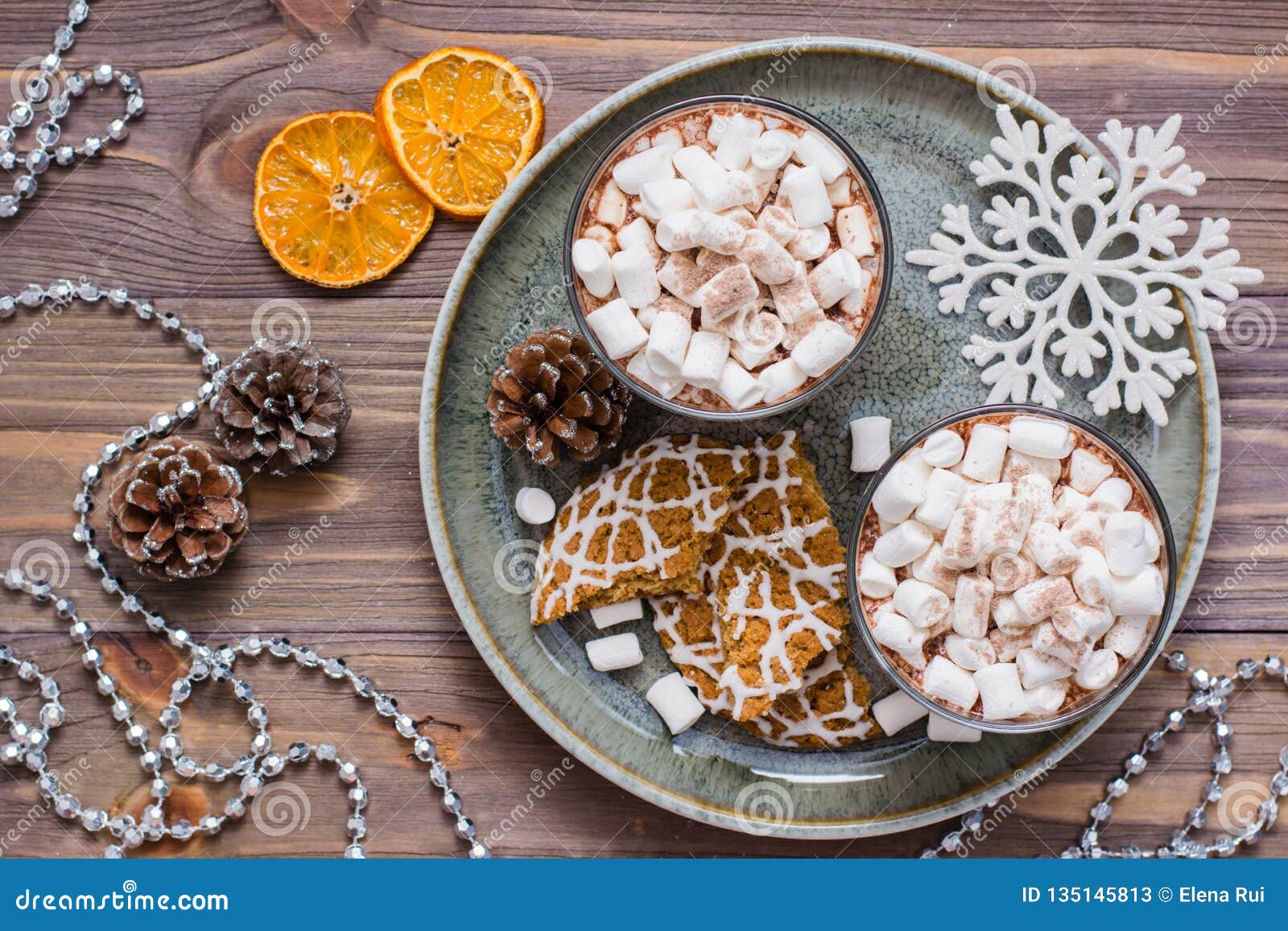 Ξηρές φέτες μανταρινιών, καυτό κακάο με marshmallows και τα μπισκότα Χριστουγέννων στον πίνακα στις διακοσμήσεις Χριστουγέννων Τοπ όψη