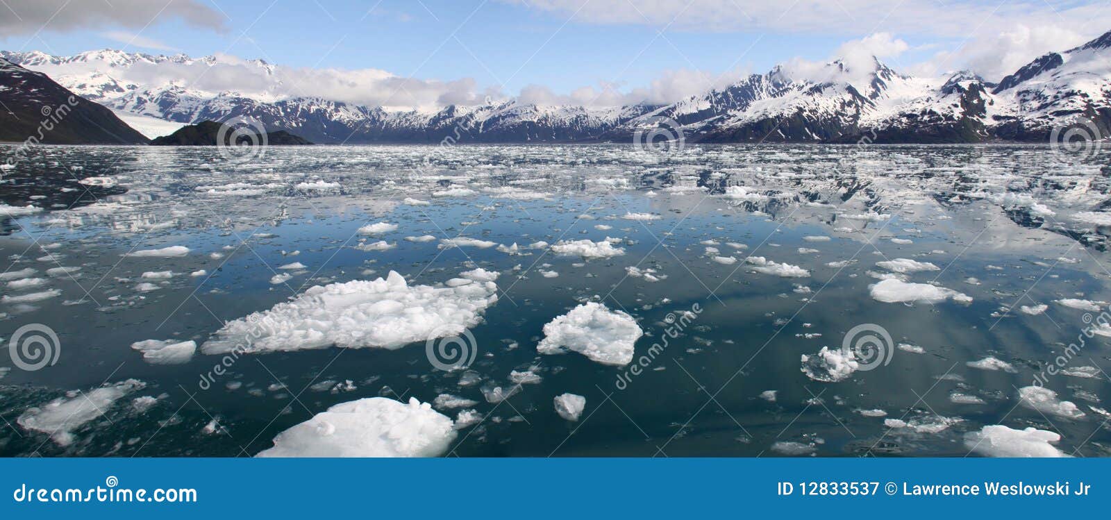 Παγόβουνα και βουνά πανοραμικά - φιορδ Kenai. Μια πρόσφατη όψη άνοιξη του παγόβουνου γέμισε τον κόλπο Aialik στο πρώτο πλάνο και το χιόνι κάλυψε τη χερσόνησο Kenai πίσω, σπίτι του ογκώδους πεδίου πάγου Harding, κοντά σε Seward στη southcentral Αλάσκα. Αυτό το τετραγωνικό εθνικό πάρκο μιλι'ου 1.760, που δημιουργείται το 1980, είναι μια από τις αρχικές εξορμήσεις/την έλξη λιμένων κρουαζιέρας από Seward, Αλάσκα. Η επικές ομορφιά και protecetd η θέση της κάνουν το μια από τις ομορφότερες θέσεις στη γη, και μια μεγάλη θέση για την παγκόσμιας ποιότητας υπαίθρια αναψυχή όπως η αλιεία, η πεζοπορία, και η επίσκεψη των κρουαζιερών.