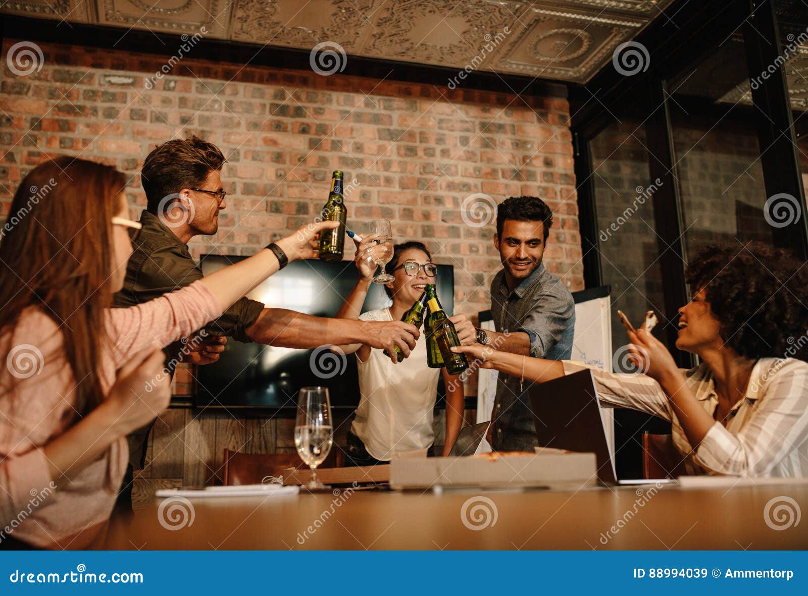 Πολυ-εθνικοί επιχειρηματίες που γιορτάζουν μια επιτυχία με τις μπύρες. Ομάδα νέων επιχειρησιακών επαγγελματιών που γιορτάζουν μια επιτυχία με τις μπύρες Διαφορετική συνεδρίαση των ομάδων ανθρώπων στη αίθουσα συνδιαλέξεων γραφείων ξεκινήματος που έχει τα ποτά πέρα από την επιτυχή επιχειρησιακή διαπραγμάτευση