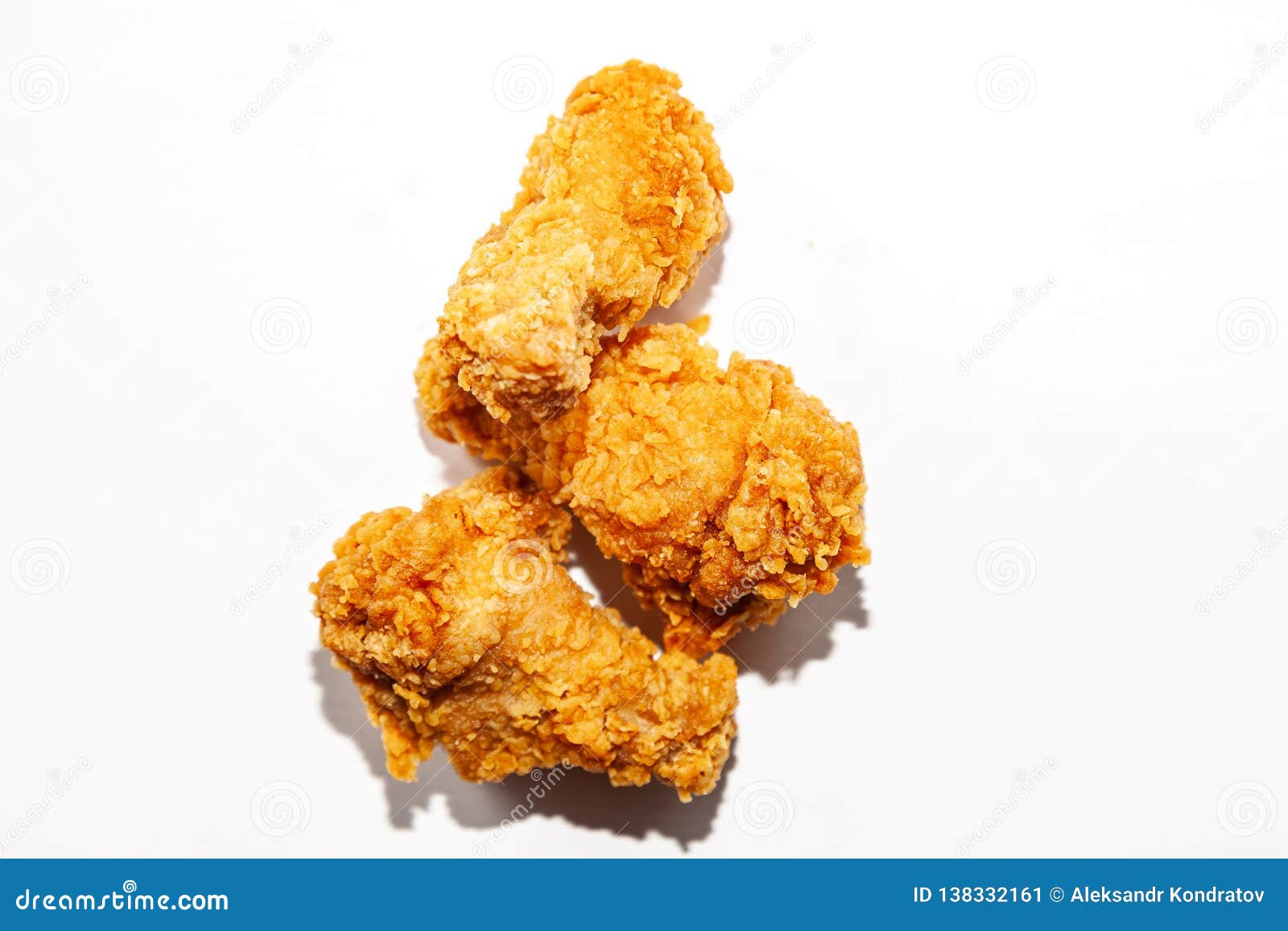 Τηγανισμένος στόμα-ποτίζοντας τρία φτερά κοτόπουλου σε μια πικάντικους σάλτσα και έναν καφετή που πασπαλίζονται με ψίχουλα σε μια χούφτα που απομονώνεται σε ένα άσπρο υπόβαθρο, ανθυγειινό λιπαρό γρήγορο φαγητό