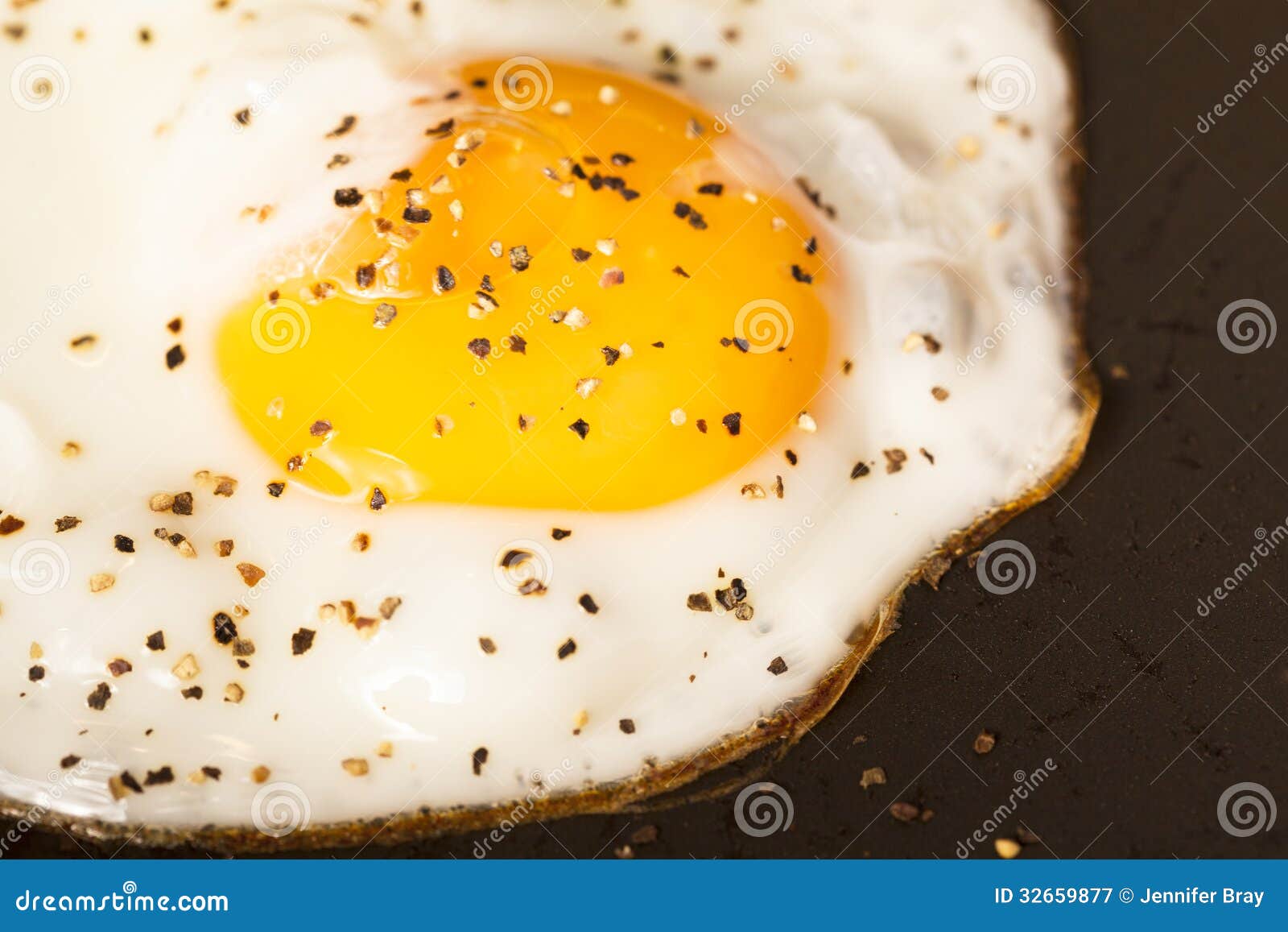 Τηγανισμένος το αυγό στο τηγάνι. Τηγάνισμα αυγών Peppered στην παν ηλιόλουστη πλευρά επάνω