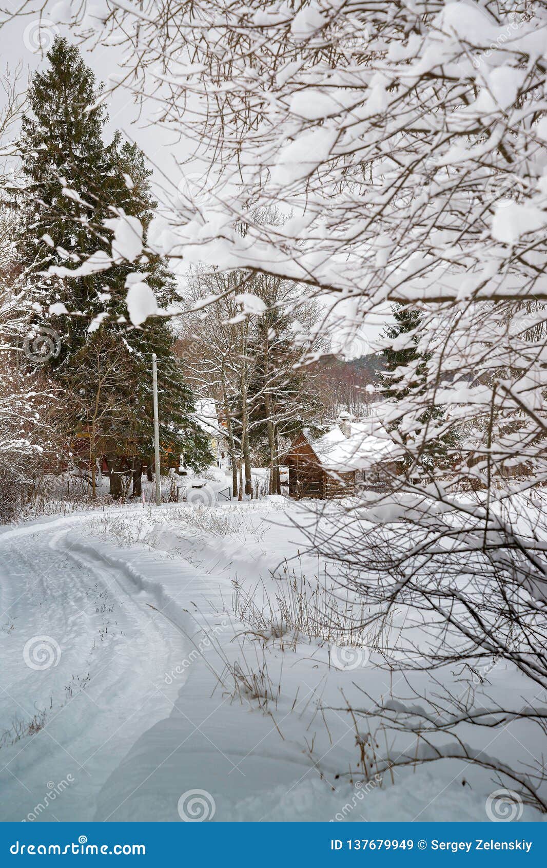 Χιονώδης, χειμερινός δρόμος στη ρωσική χώρα με το τεράστιο κομψό και ξύλινο σπίτι κάτω από το χιόνι