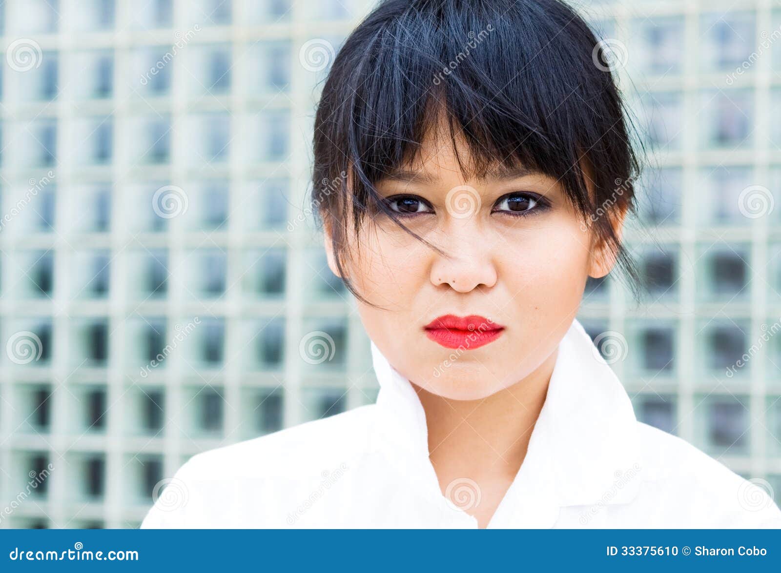 Όμορφη ασιατική γυναίκα στη σύγχρονη ρύθμιση, που φορά ένα άσπρο πιαμένο πουκάμισο.