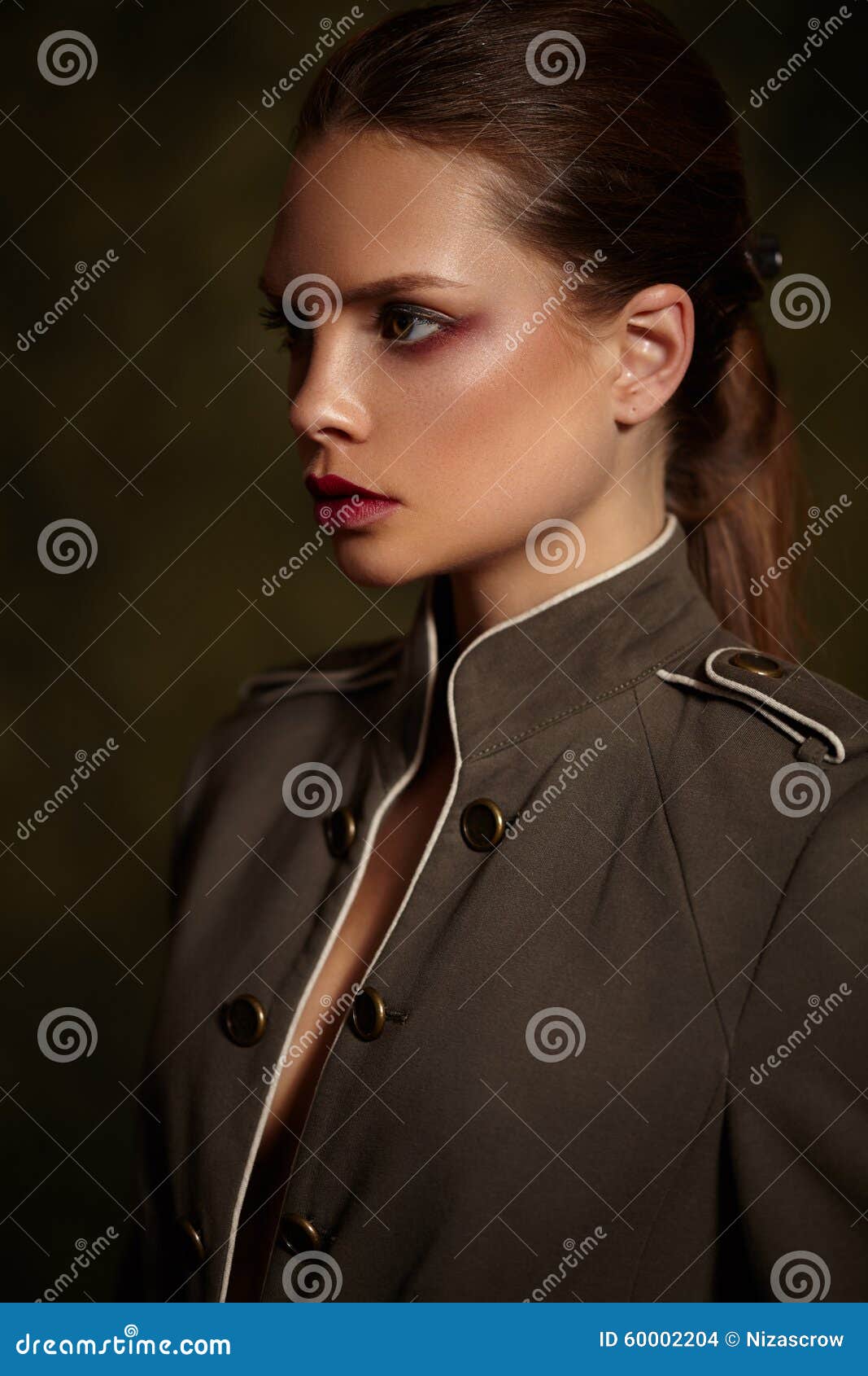 Όμορφο κορίτσι στο μοντέρνο παλτό στο σκοτεινό υπόβαθρο. Όμορφο κορίτσι σε ένα μοντέρνο παλτό σε ένα σκοτεινό υπόβαθρο Φωτεινά κόκκινα χείλια