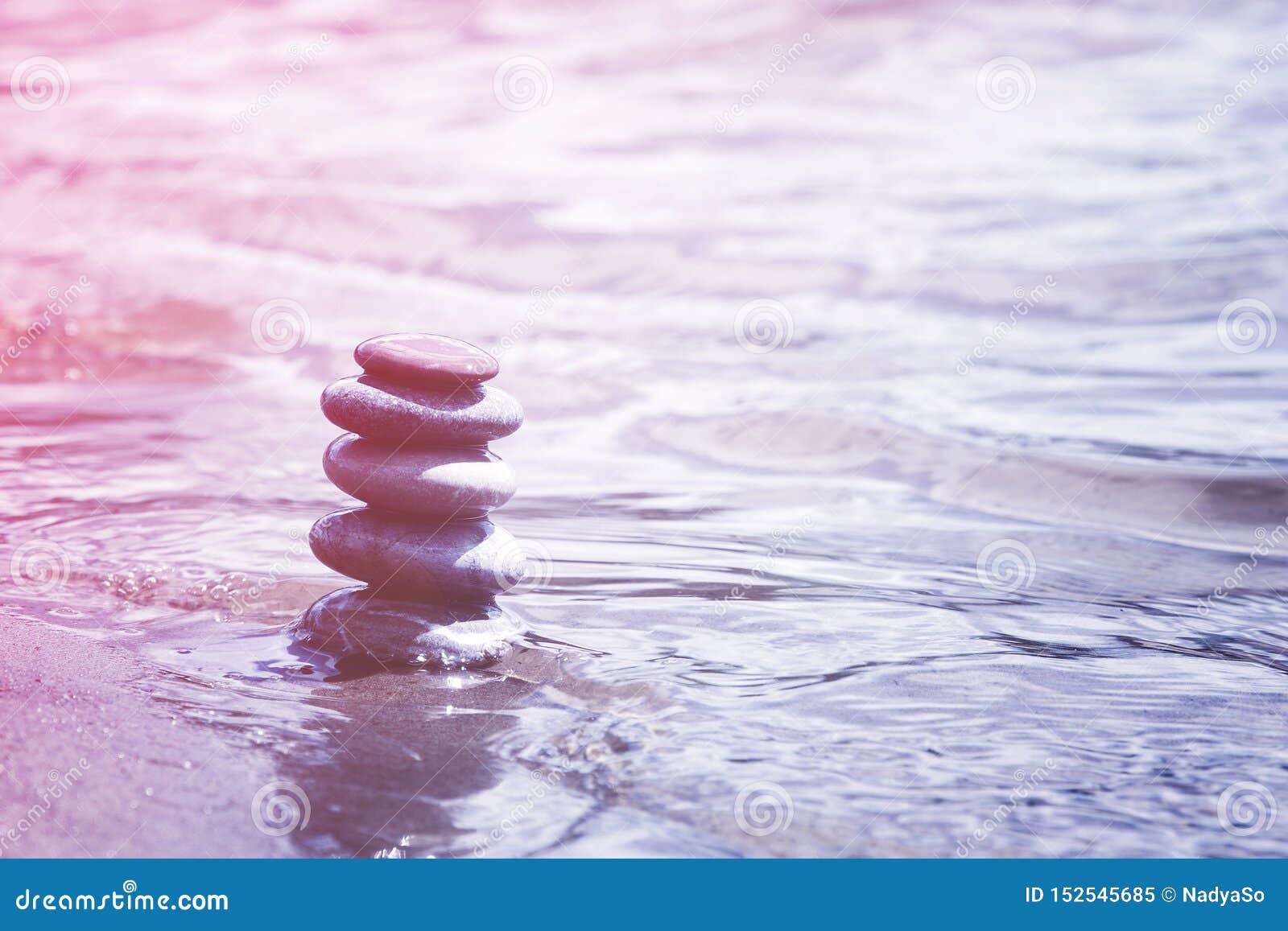 Балансируя камешки в символе воды, раздумья, сработанности и дзэна. Пирамида балансируя камешков на крае воды Созерцание, раздумье, символ дзэна, пинк и пурпурный мягкий тон