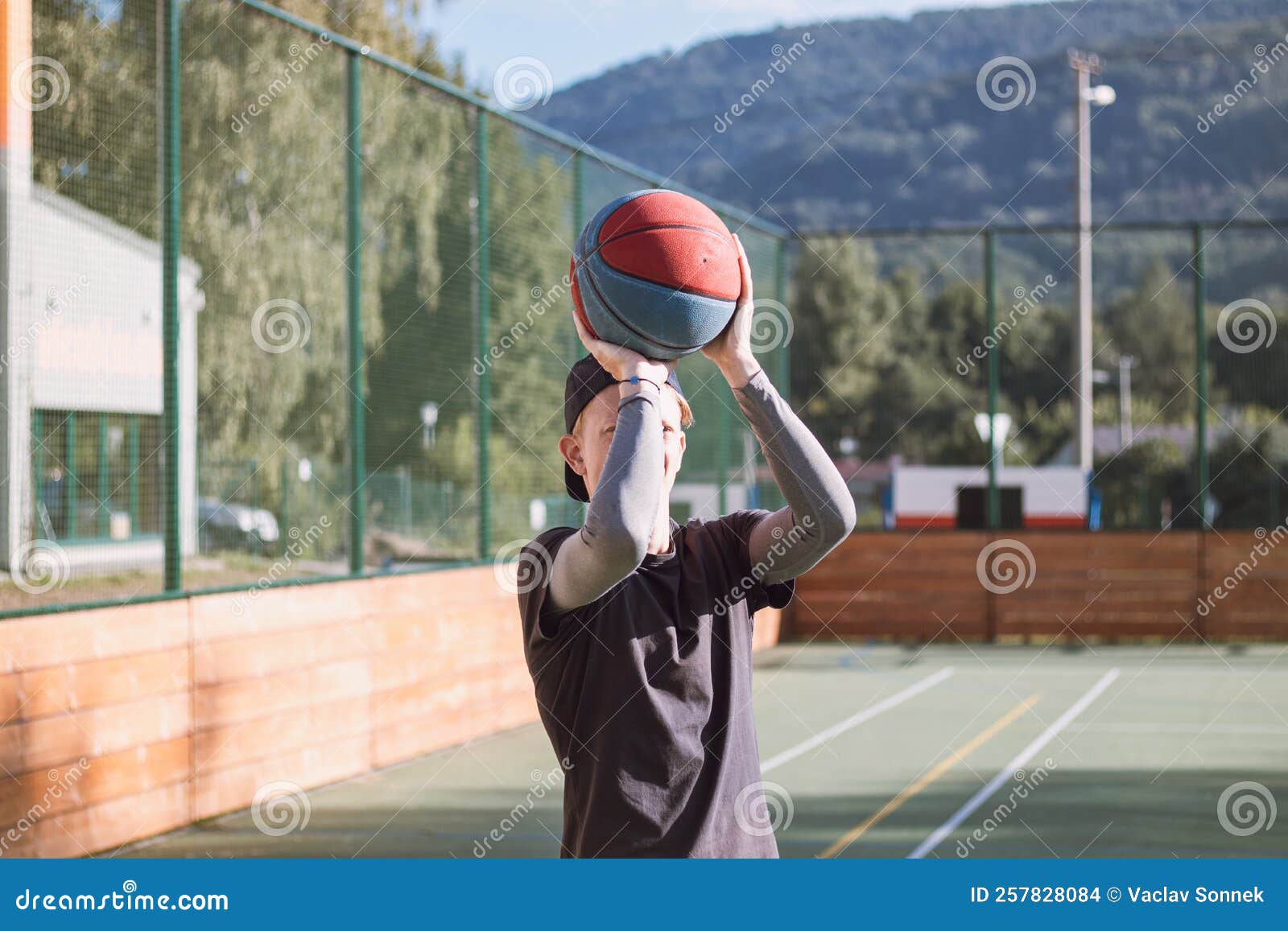 блондинка в спортивной практике стреляет в баскетбол из-за трёхугольной ...