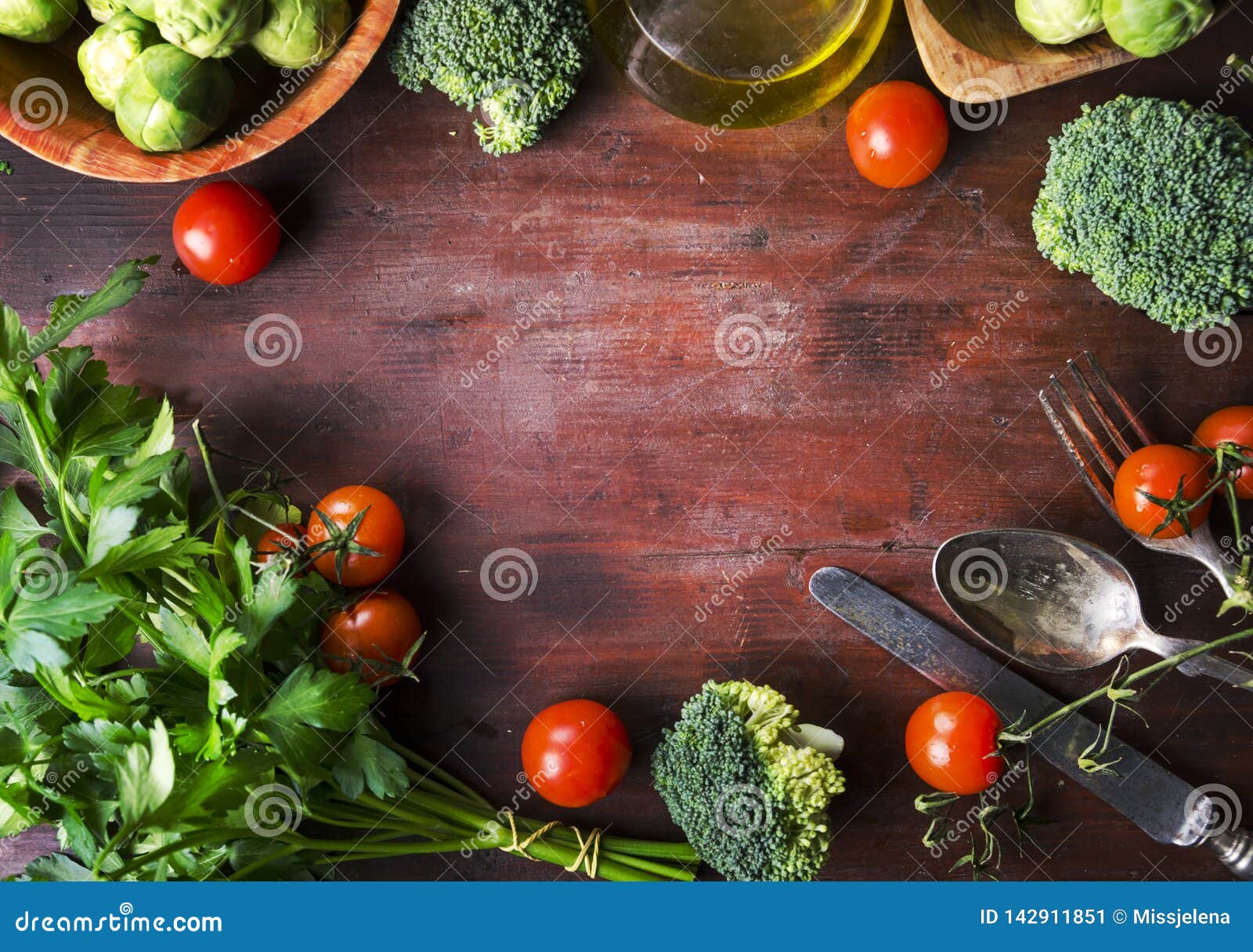 Взгляд сверху здоровой рамки пищевых ингредиентов на винтажном деревянном столе Граница смешивания овоща Superfood на деревенской предпосылке сверху Томат вишни, росток Брюссель, брокколи, петрушка, зеленые цвета и накладные расходы оливкового масла