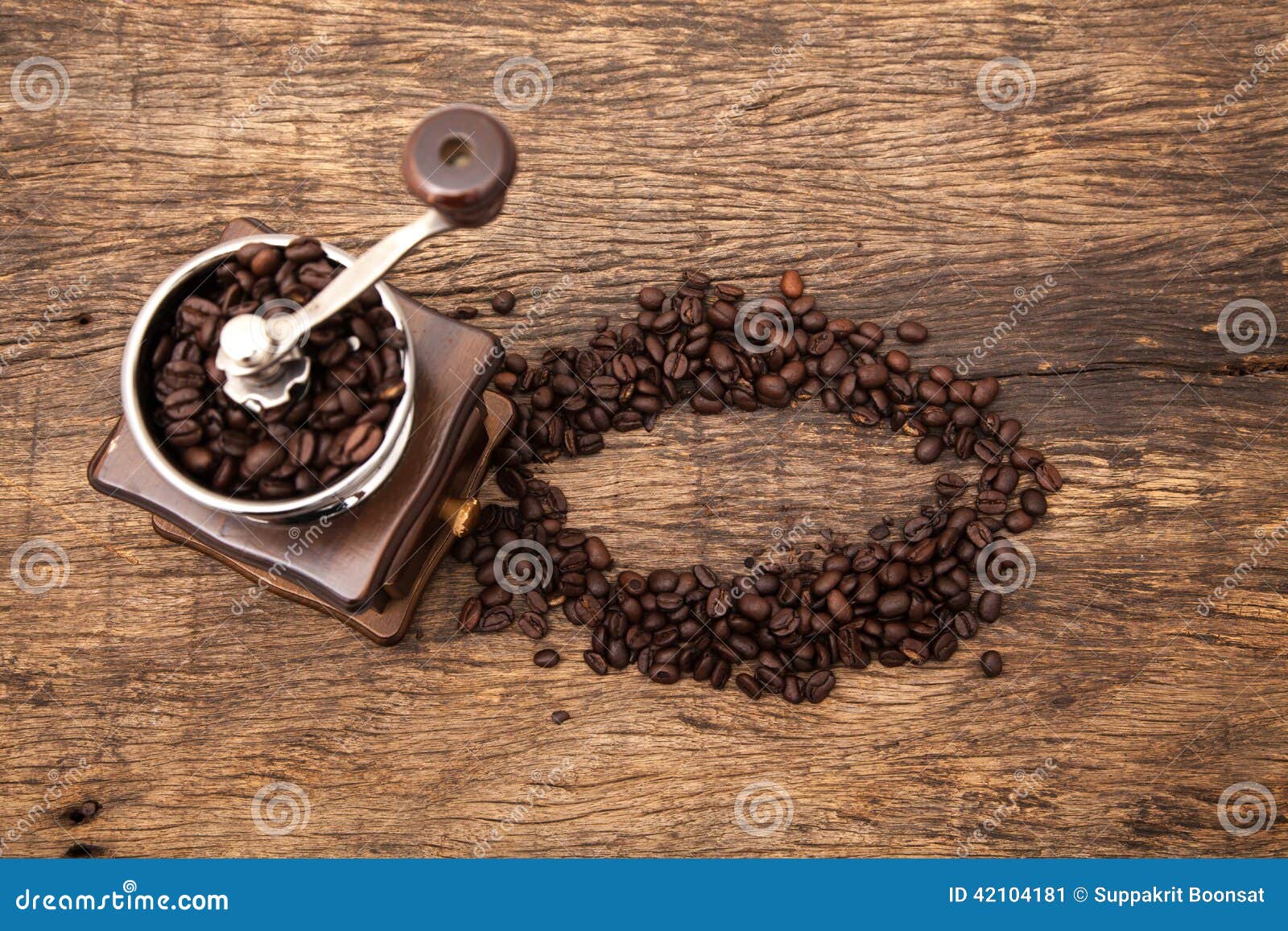 Винтажный точильщик кофейного зерна рядом с кофейными зернами формы круга на верхней части деревянного стола как предпосылка