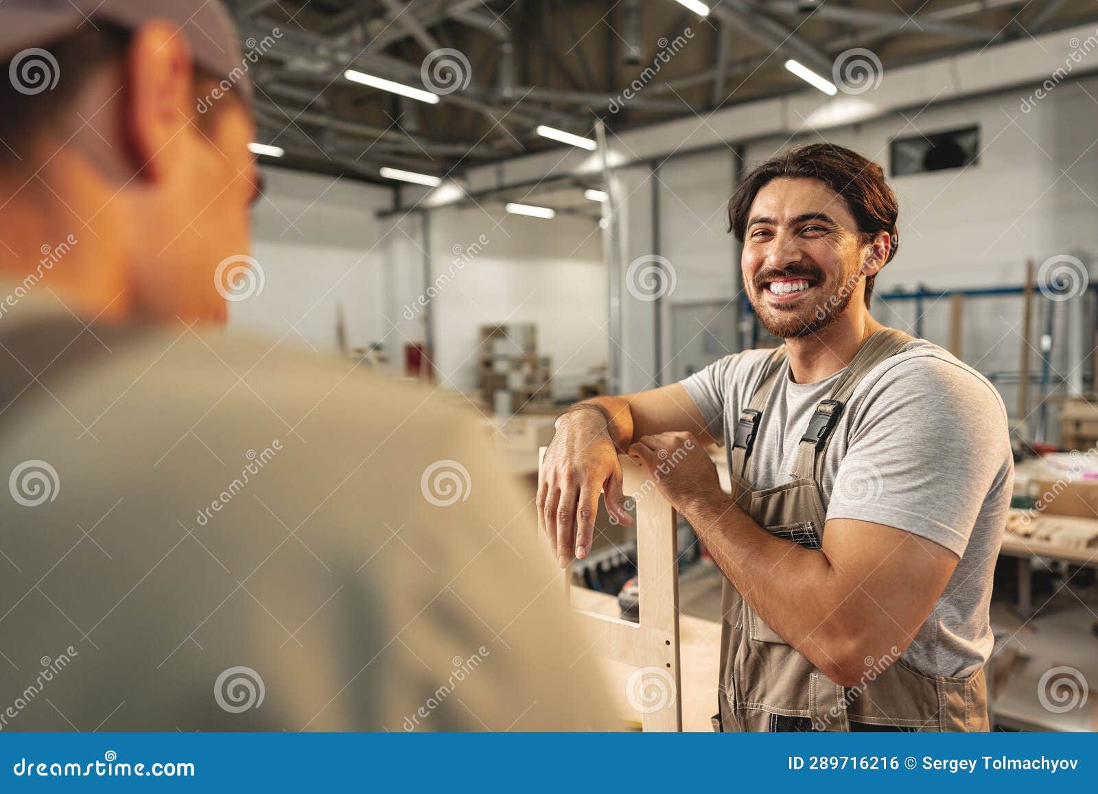 два молодых человека плотники делают мебель на складе деревянной ...