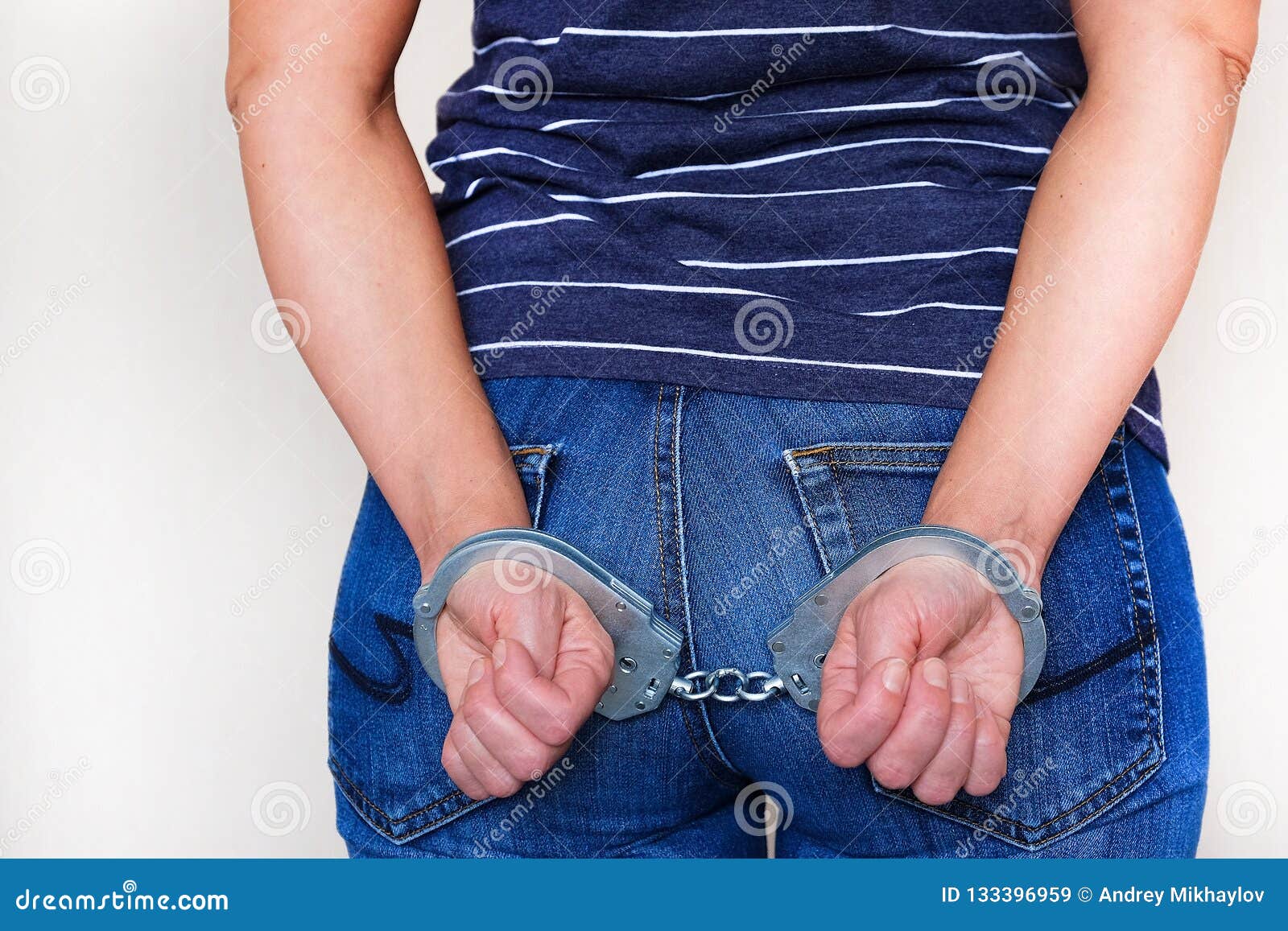 Вид сбоку женщины в наручниках за спиной.