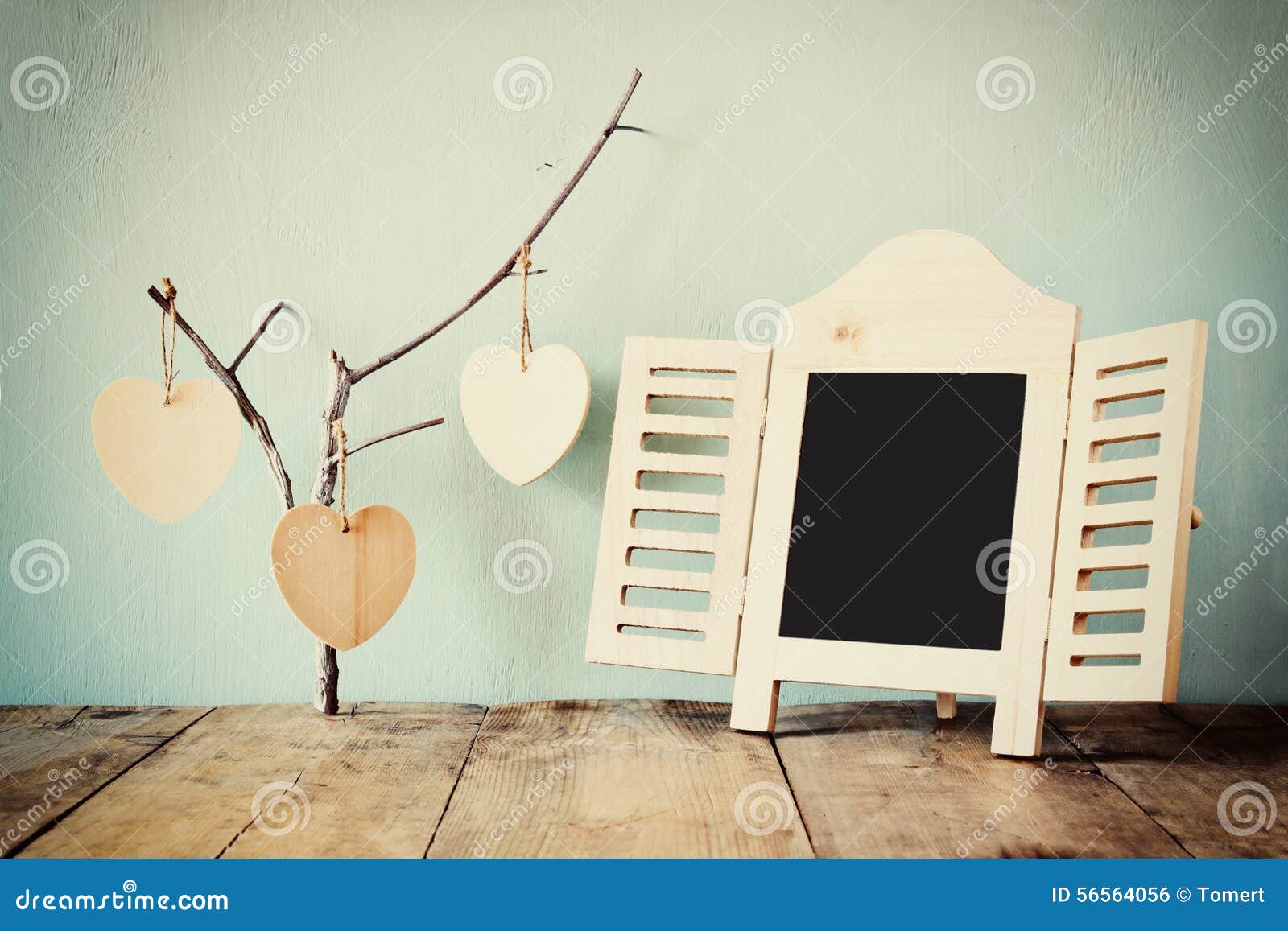 Декоративная рамка доски и деревянные сердца смертной казни через повешение над деревянным столом подготавливайте для текста или модель-макета ретро фильтрованное изображение