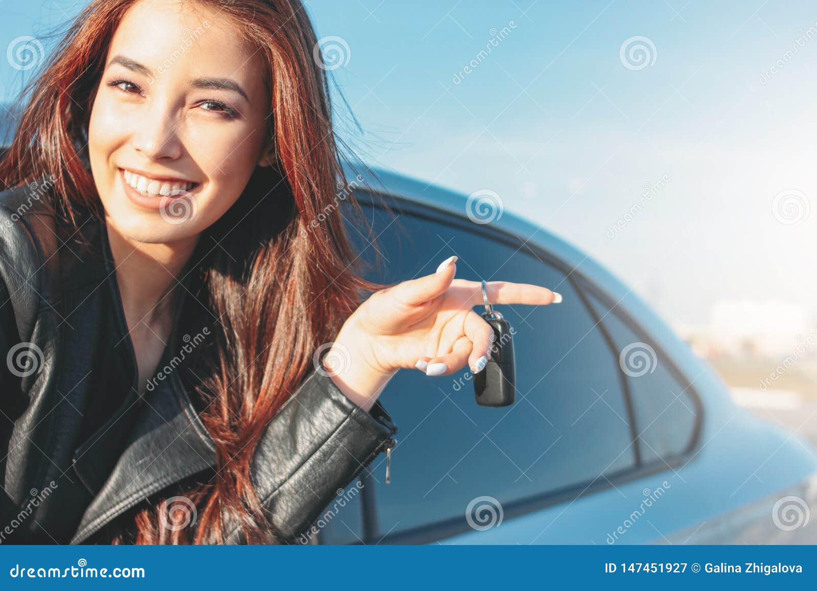 Женщина длинных волос брюнета Happpy красивая очаровывая молодая азиатская в черной кожаной куртке с ключом автомобиля