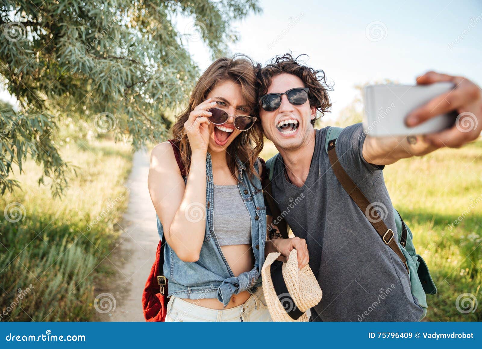 Жизнерадостные пары w в лесе и делая selfie. Пары w детенышей усмехаясь счастливые жизнерадостные в лесе и делая selfie