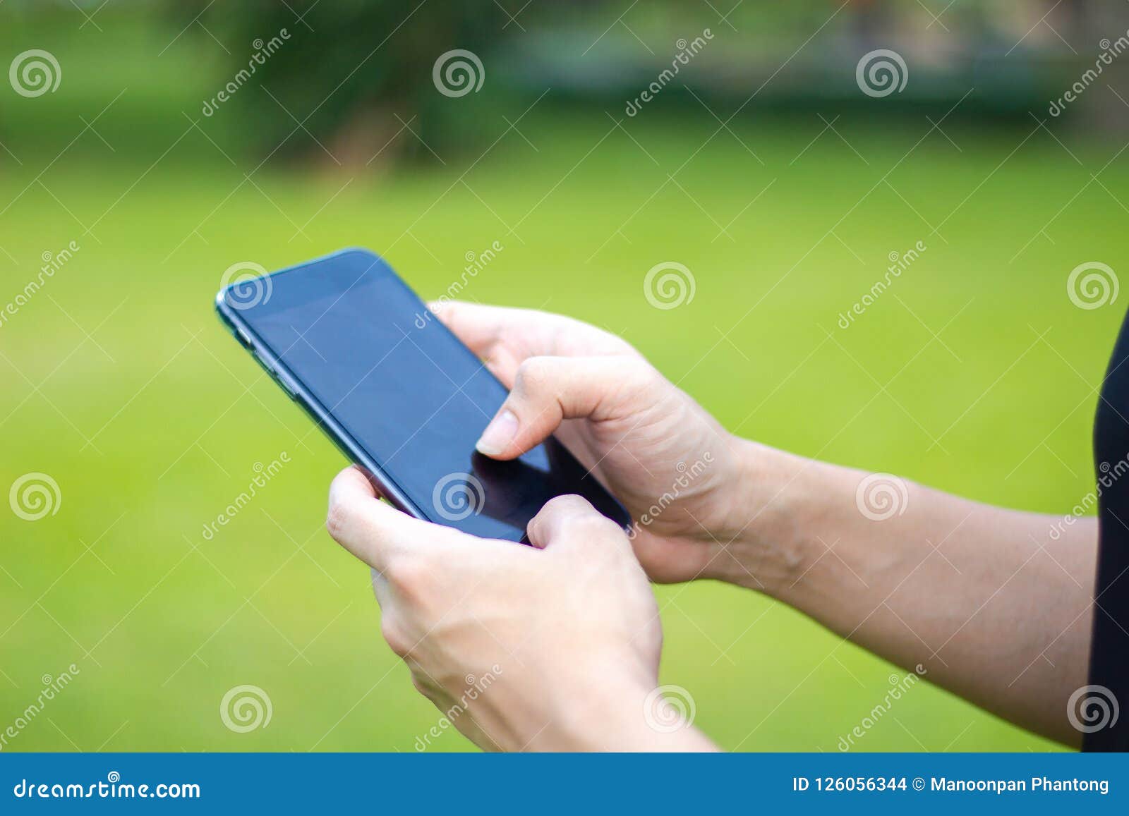 Закройте вверх человека используя мобильный умный телефон в парке руки к. Закройте вверх человека используя мобильный умный телефон в парке мобильный телефон экранного дисплея касания рук