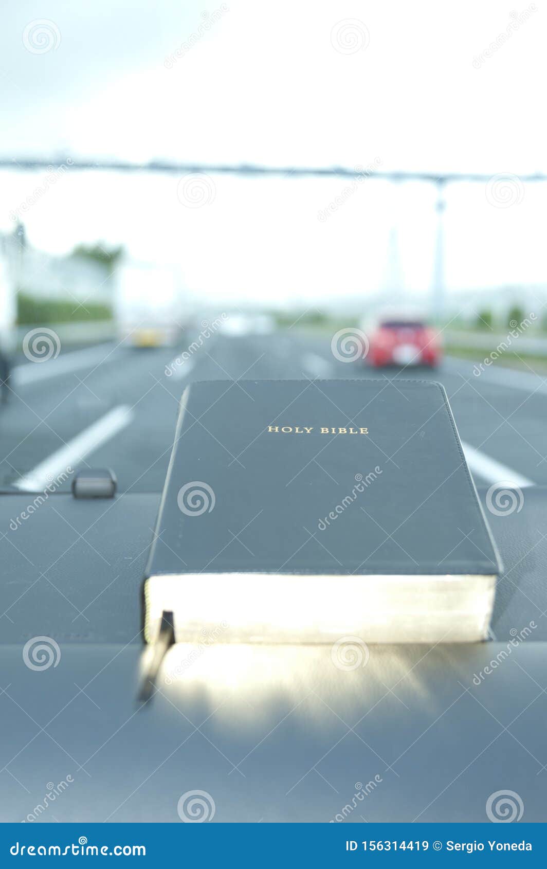 Закрытая библия с золотым светом Автомагистраль с размытым фоном с автомобилями Копировать пространство Вертикальный выстрел