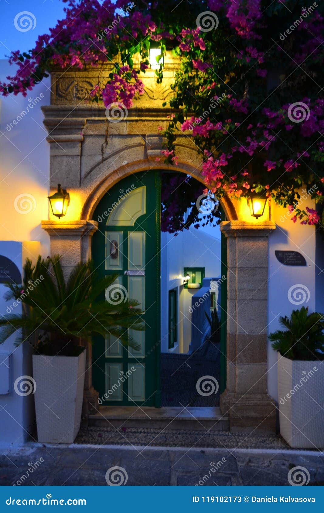 Зеленые двери украсили теплые света и розовые цветки, зеленое растение. Зеленые двери украсили теплые света и розовые цветки, фото зеленого растения принятое в старый городок Rhodos, Греции
