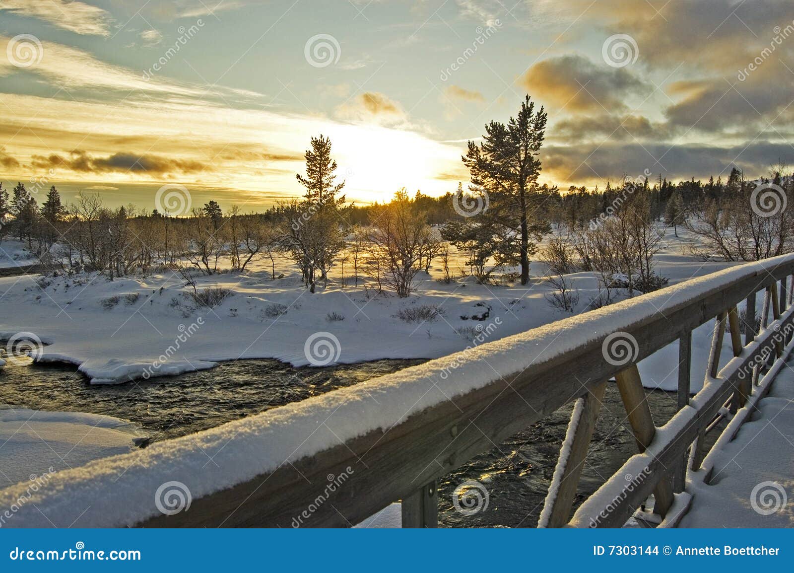 зима ландшафта. мост покрыл ледистое над заходом солнца снежка реки